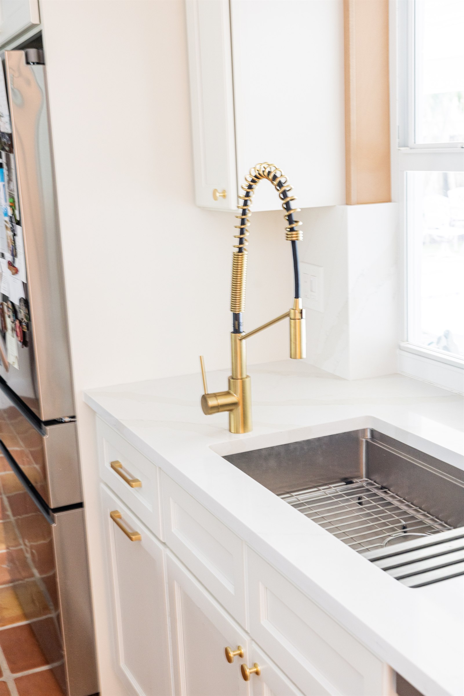 Accessible prep sink with brass gooseneck faucet set at an easy-reach height beneath a marble backsplash