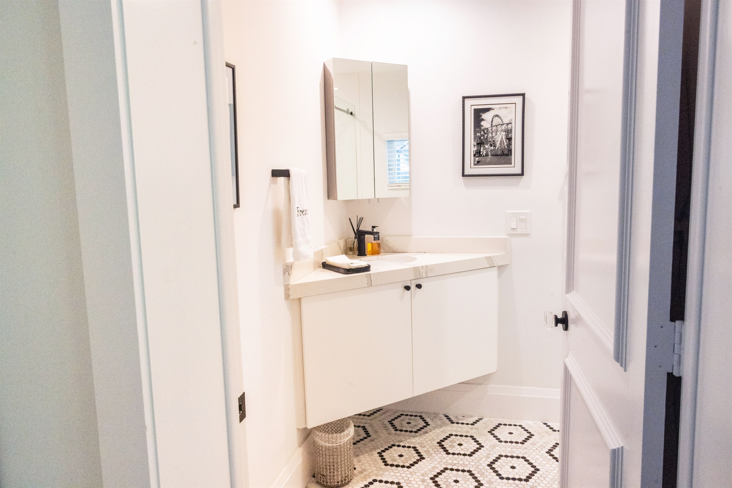 Corner powder room vanity with a Navy Pier photograph and mirrored medicine cabinet