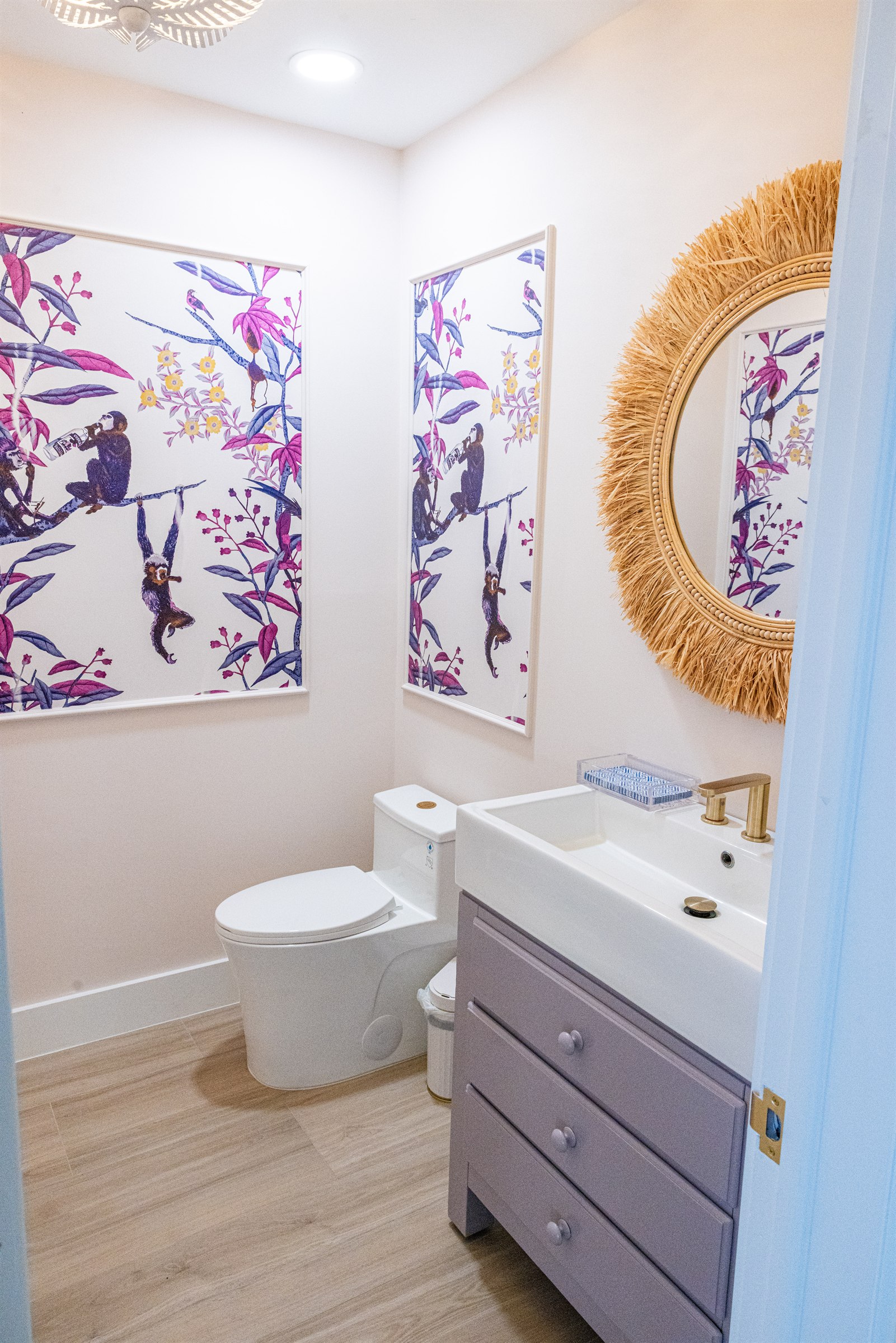 Whimsical powder room with colorful monkey wallpaper and lavender vanity