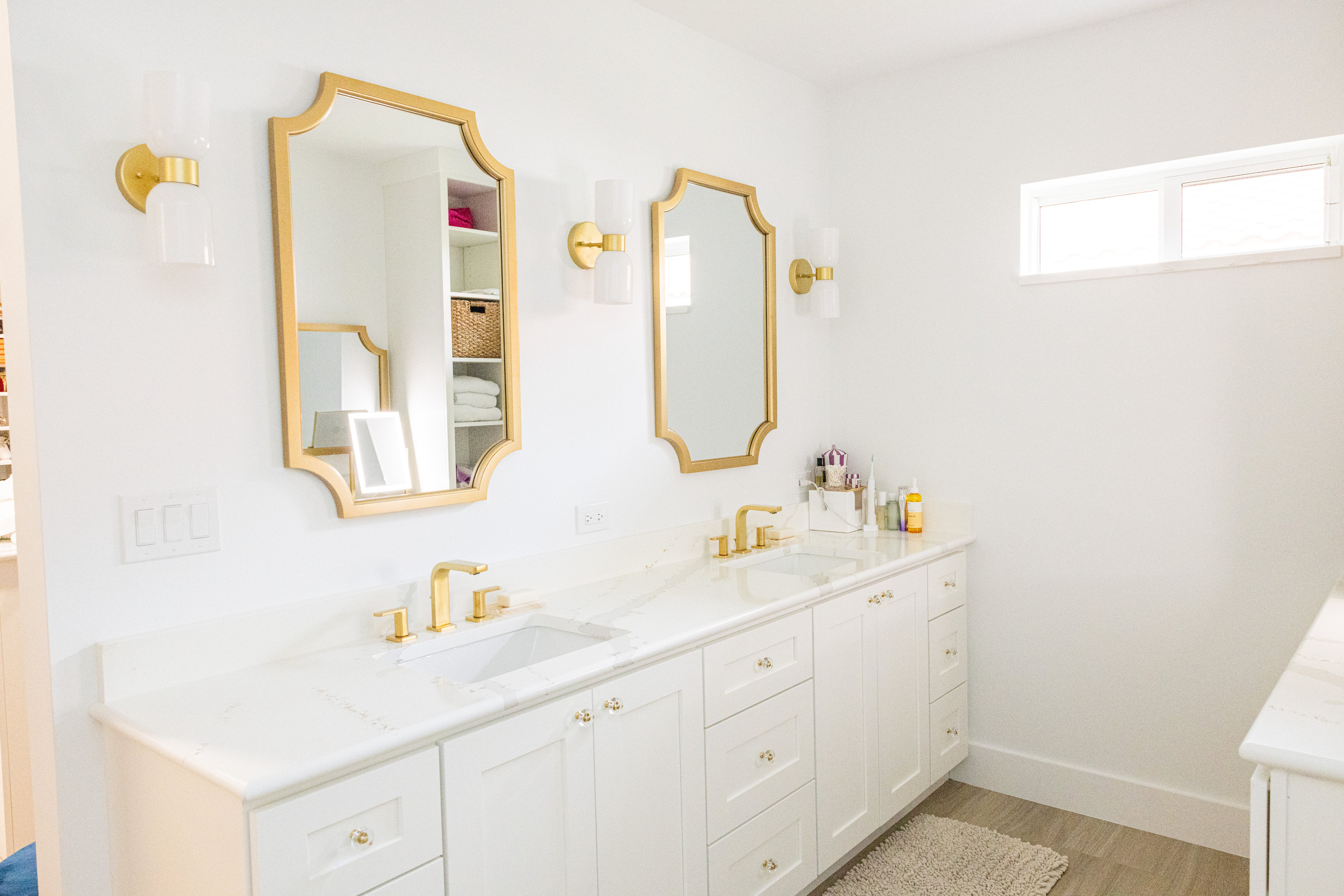 Master bath with double vanity, gold mirrors and marble finishes