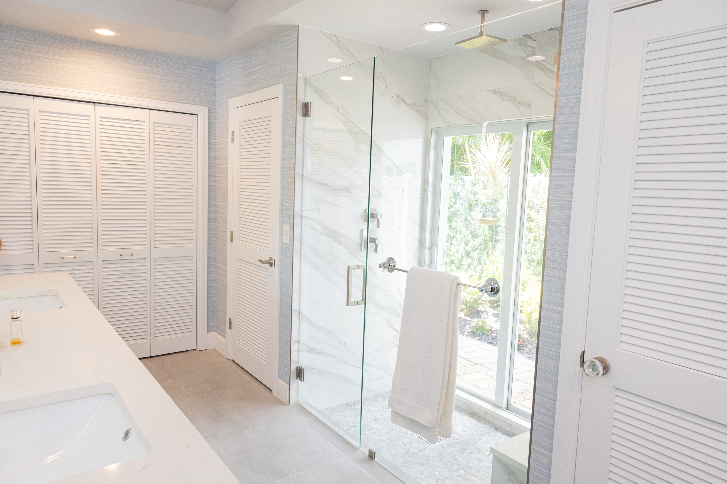 Master bath walk-in shower with marble tile and garden window view