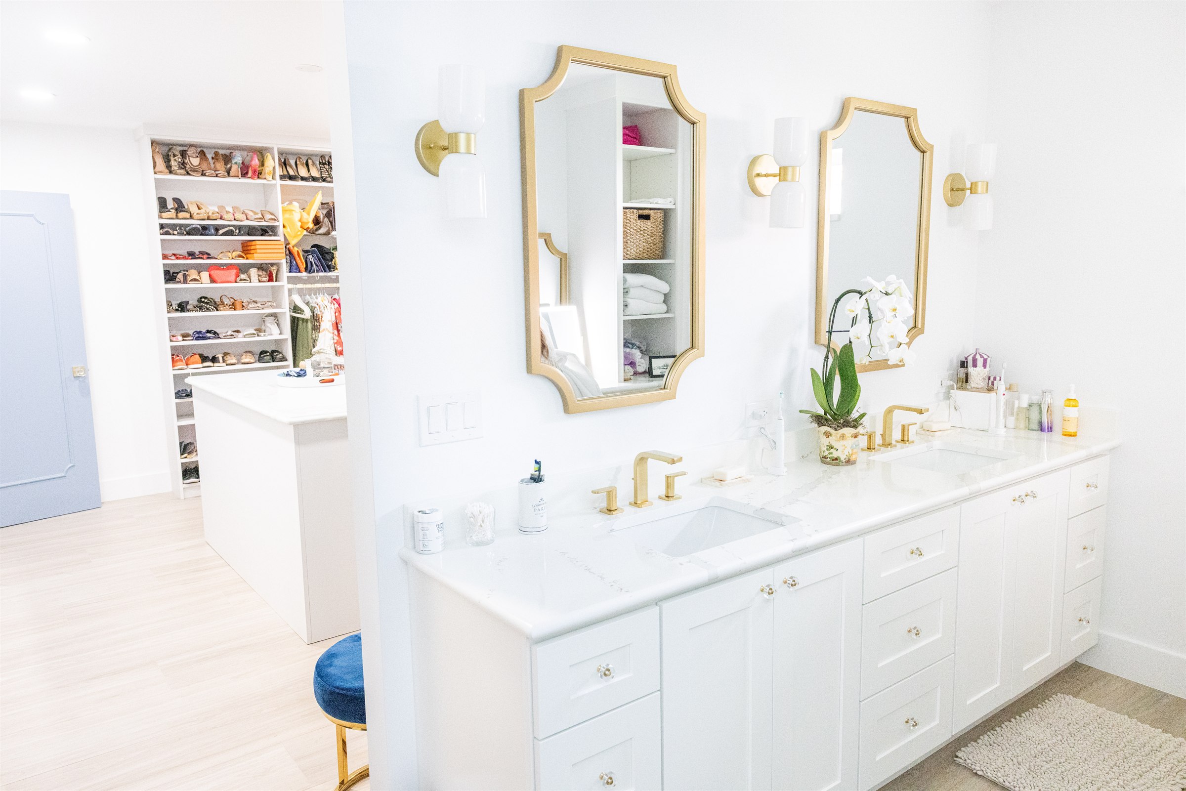 Double vanity with gold octagonal mirrors, brass faucets, and walk-in closet view