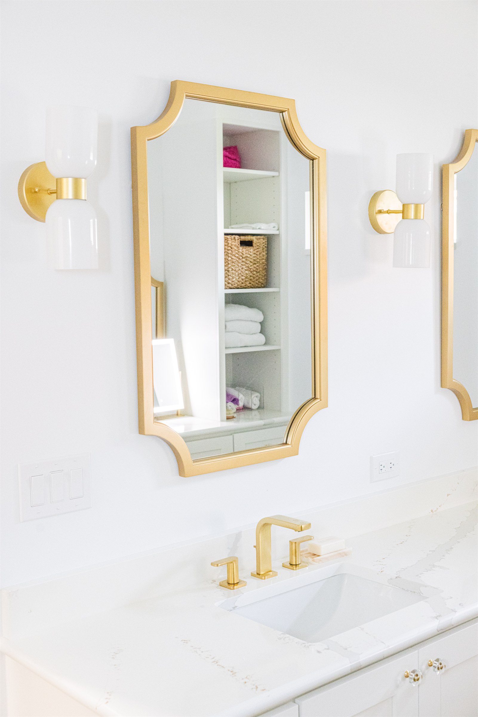 Detail of a gold scalloped mirror reflecting the linen closet shelving
