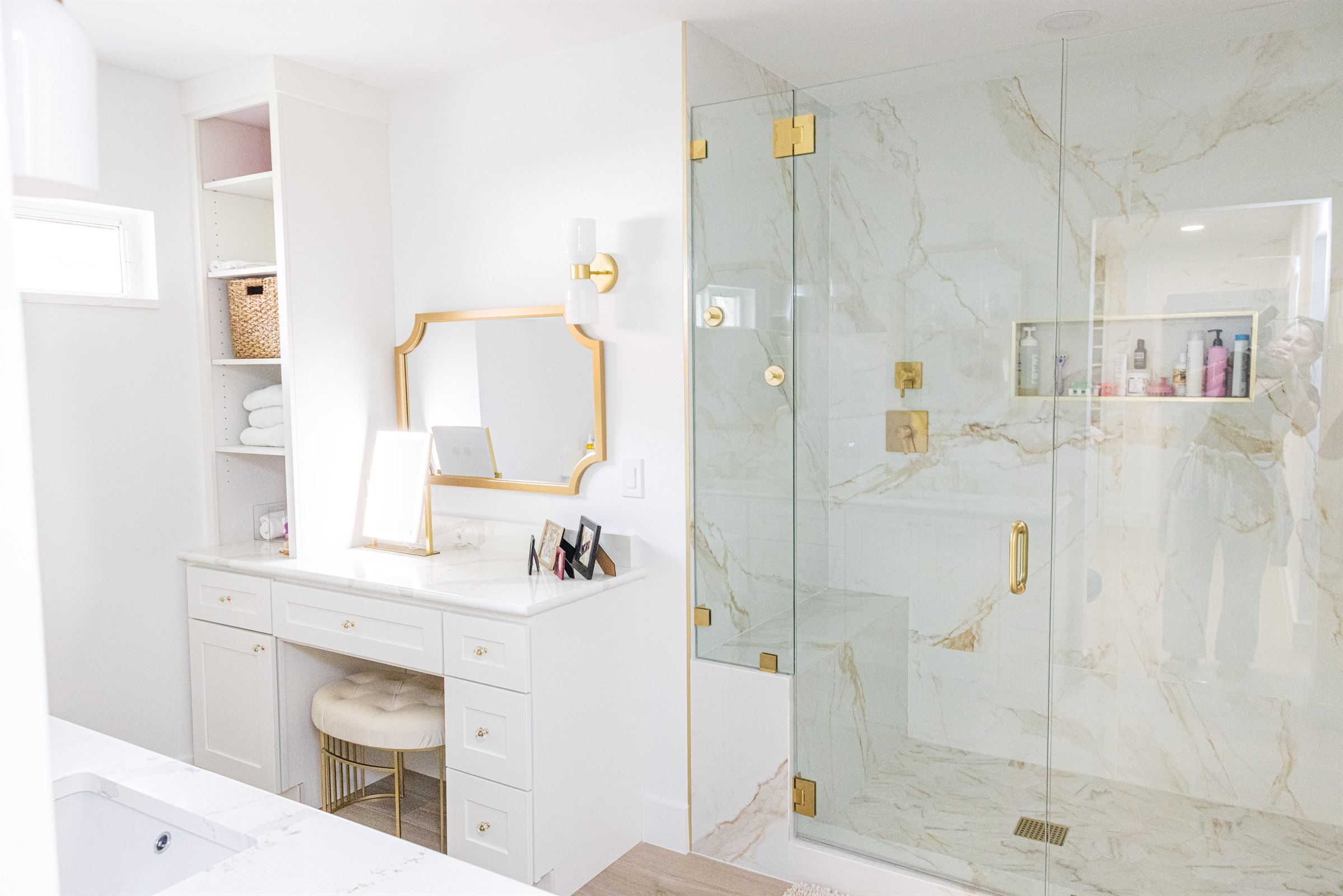 Makeup vanity nook beside a floor-to-ceiling marble shower enclosure
