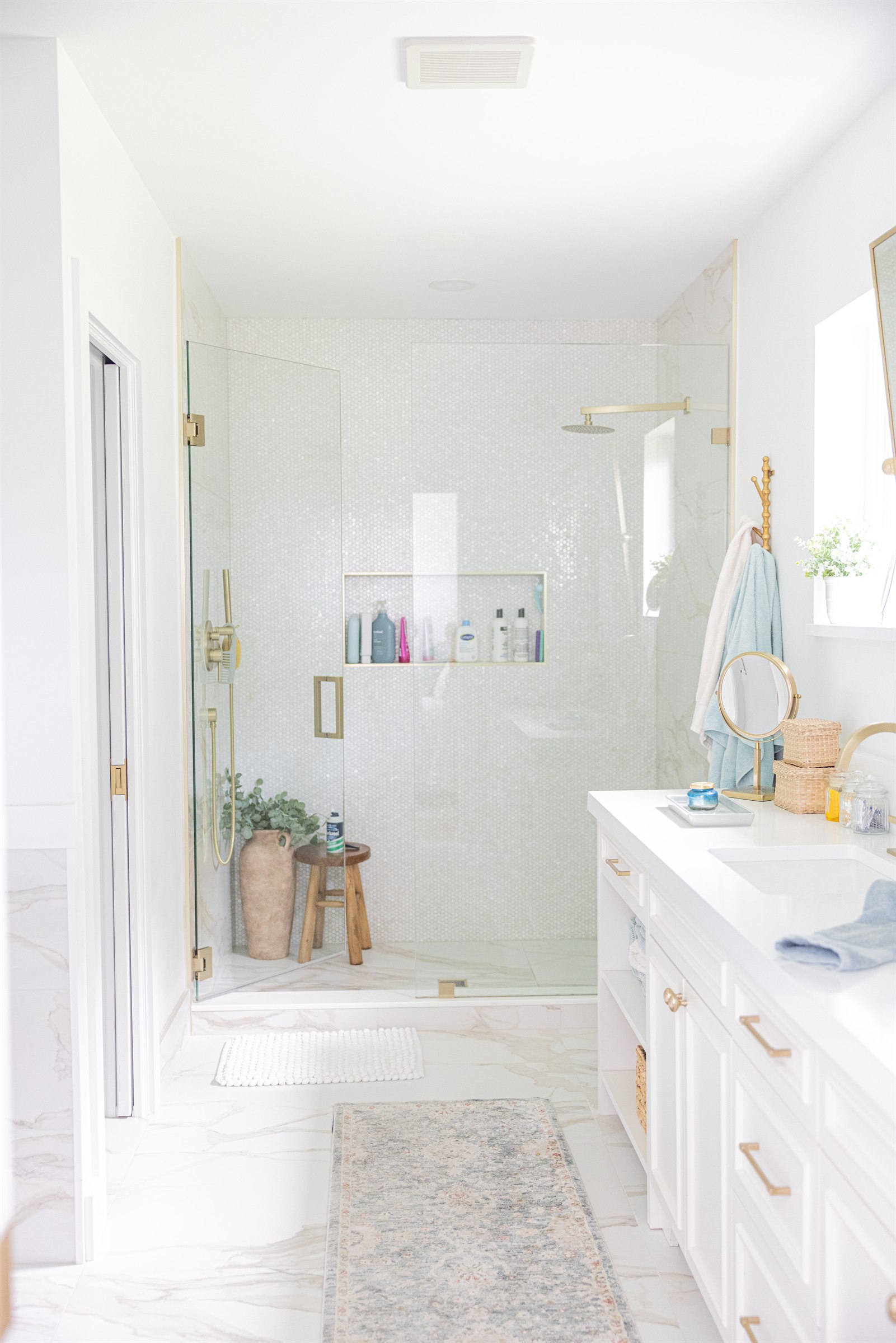 Glass-front display cabinets and mirror reflecting the marble shower and closet
