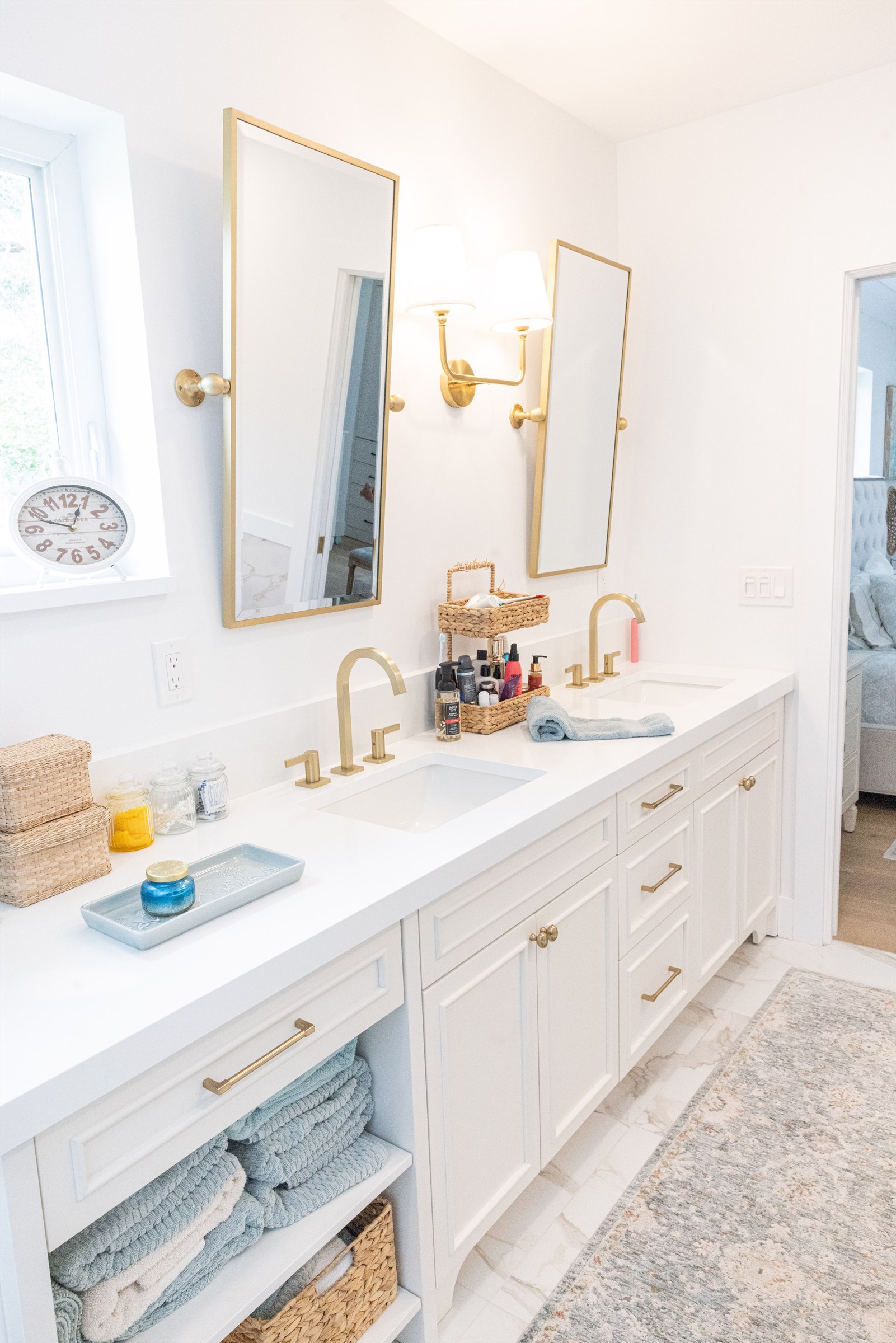 Double vanity with pivoting gold-framed mirrors and folded towel storage