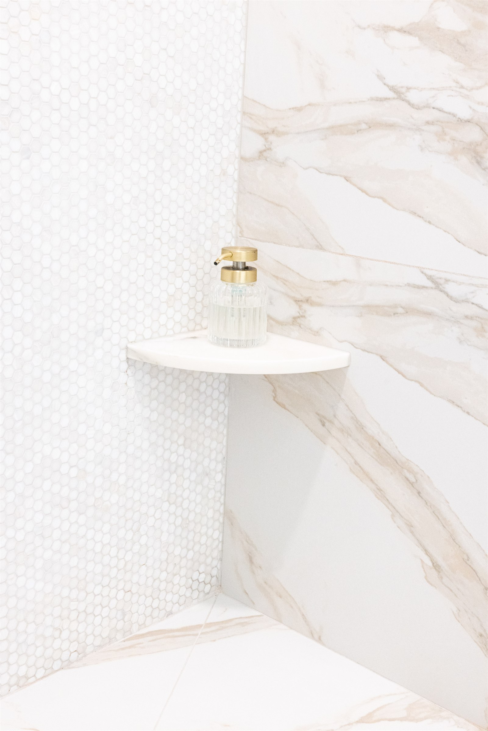 Detail of a marble shower corner shelf with a glass soap dispenser