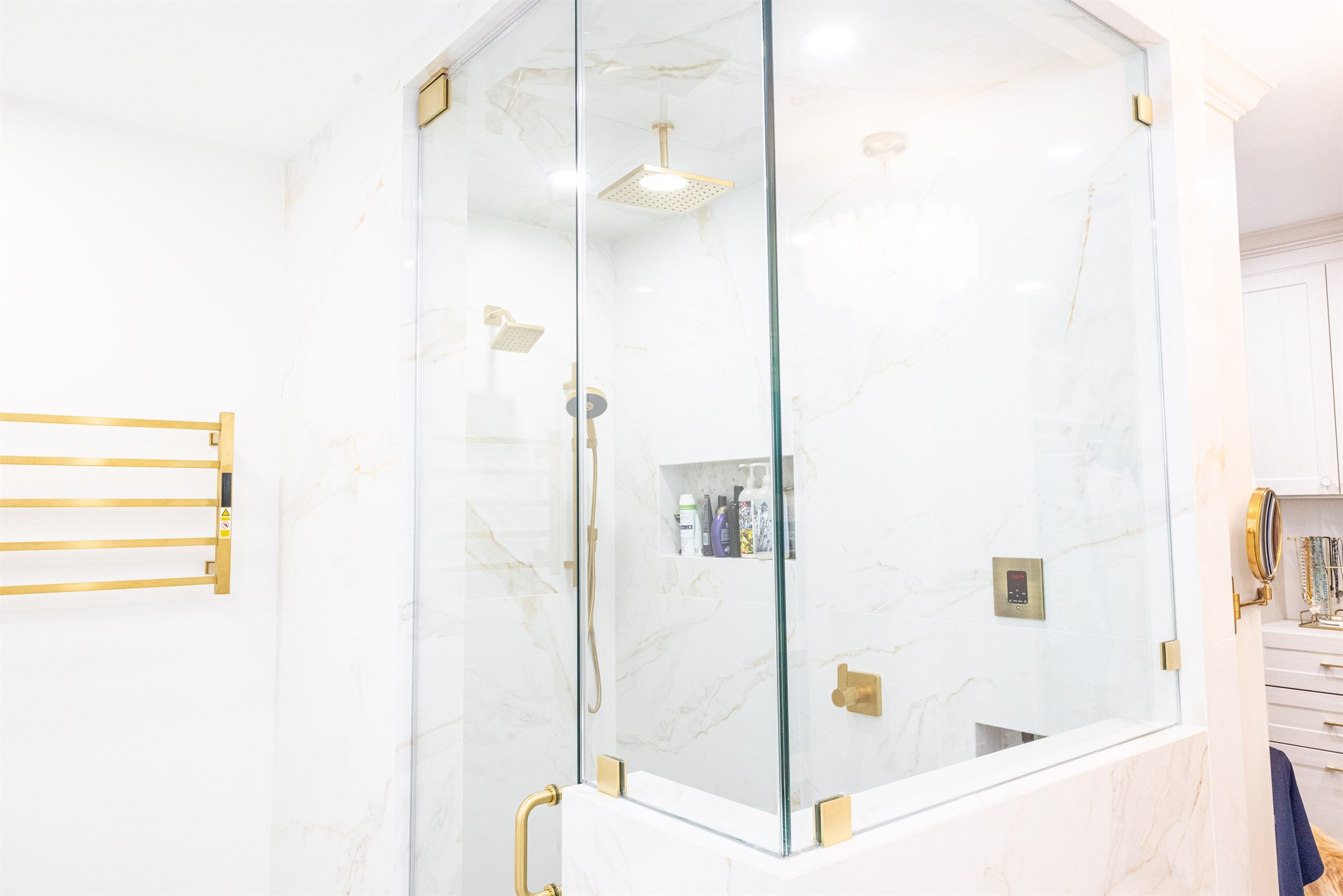 Glass-front cabinetry beside a mirror reflecting the walk-in closet and shower