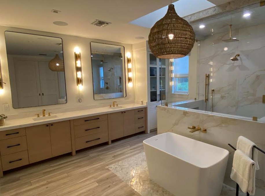 Wide view of the primary bath spanning the double vanity, soaking tub, and glass shower