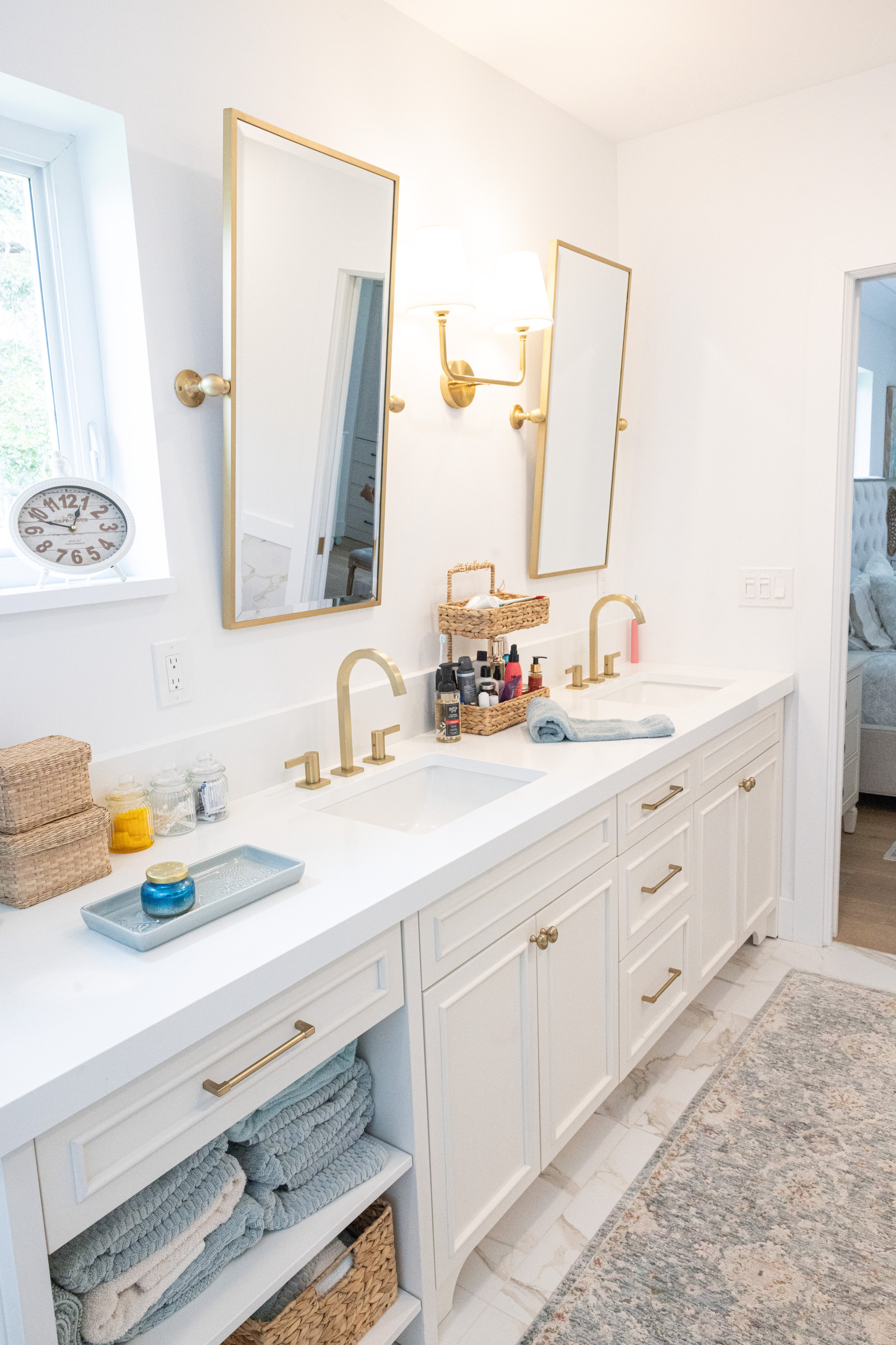 Master bath double vanity with gold rectangular mirrors and open shelving