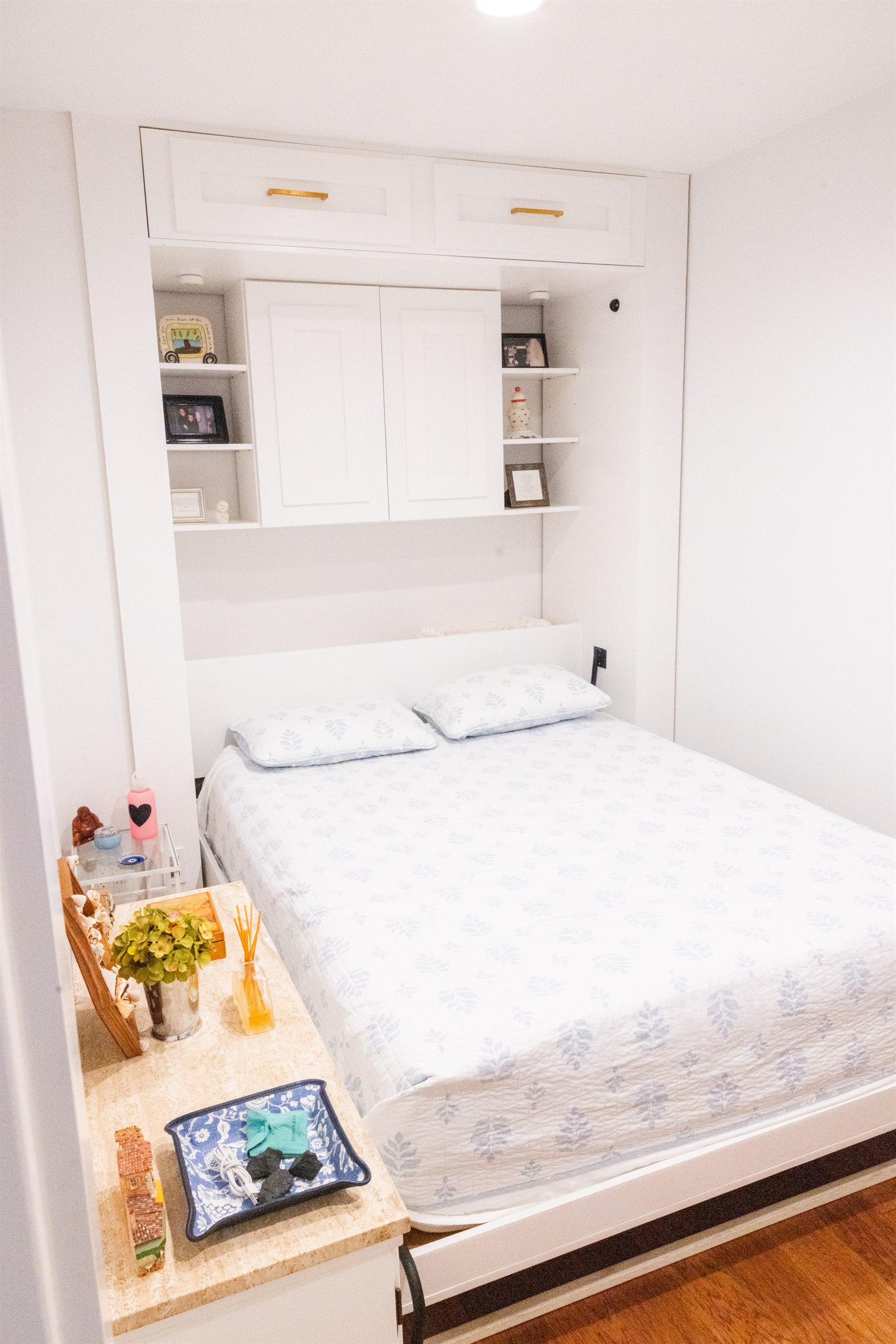 Guest bedroom built-in with white cabinetry, brass pulls, and a bedside vanity nook
