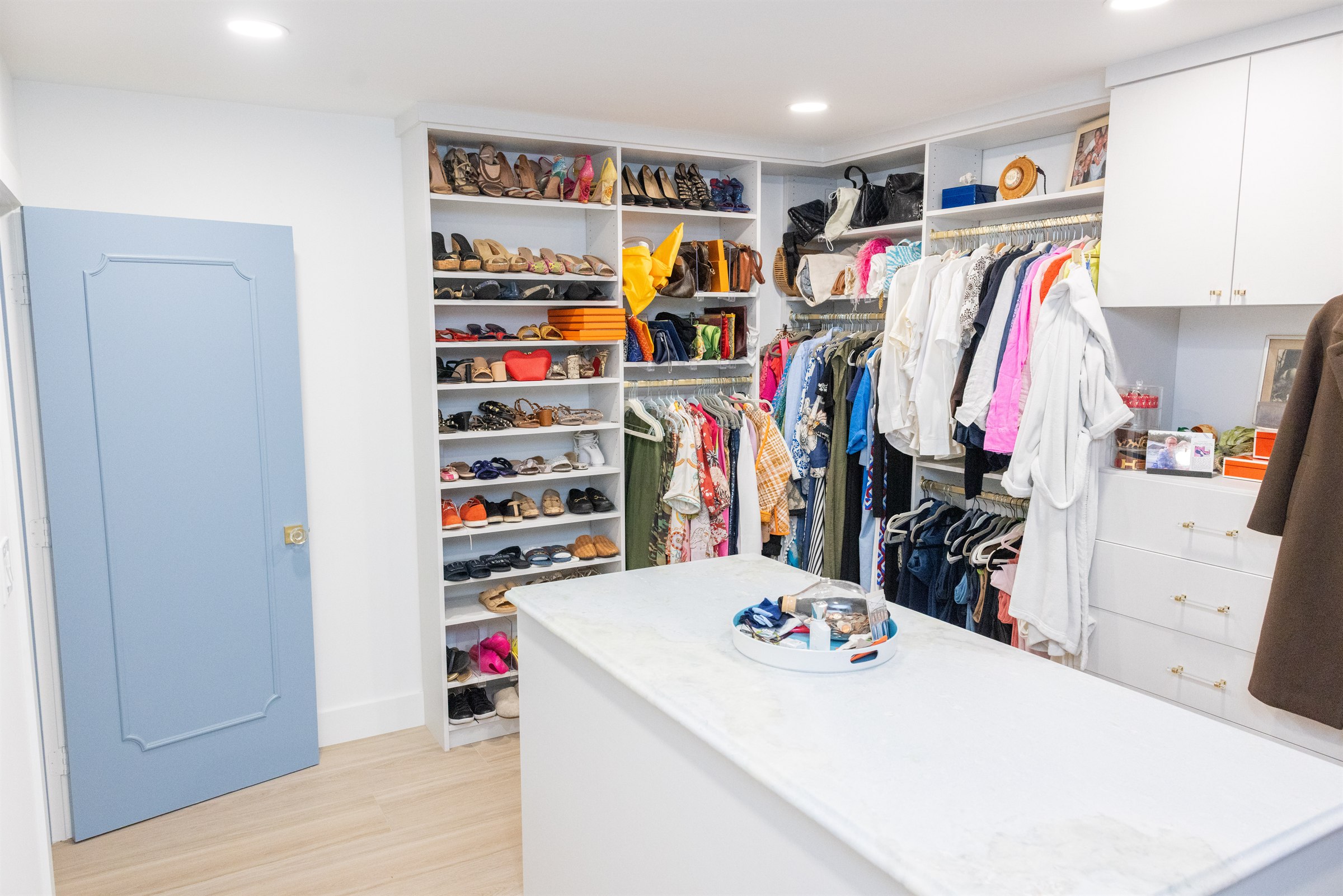 Walk-in closet with floor-to-ceiling shoe shelving, handbags, and marble center island