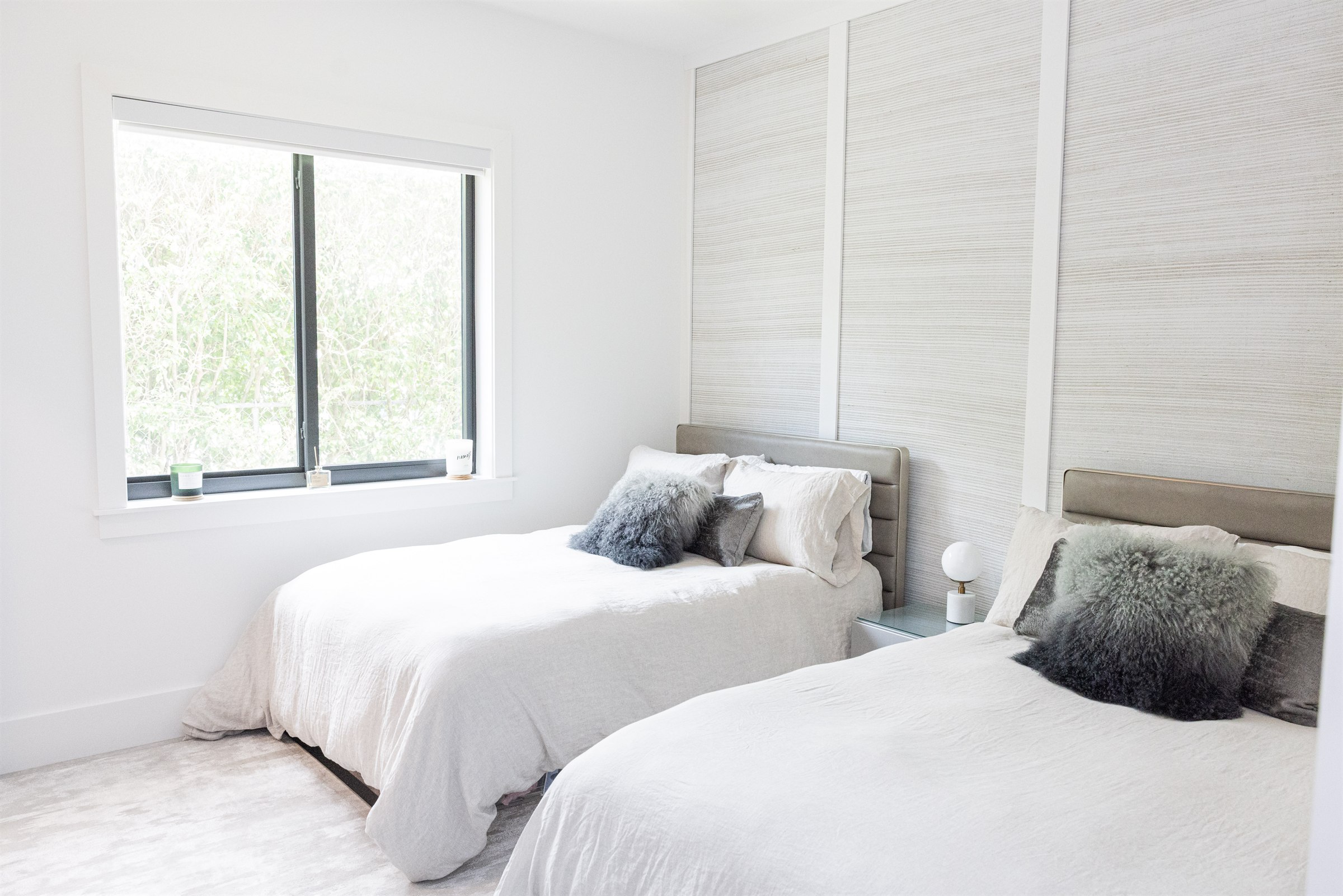 Master bedroom wide view with tufted headboard, blue accent pillow, and wicker armchair