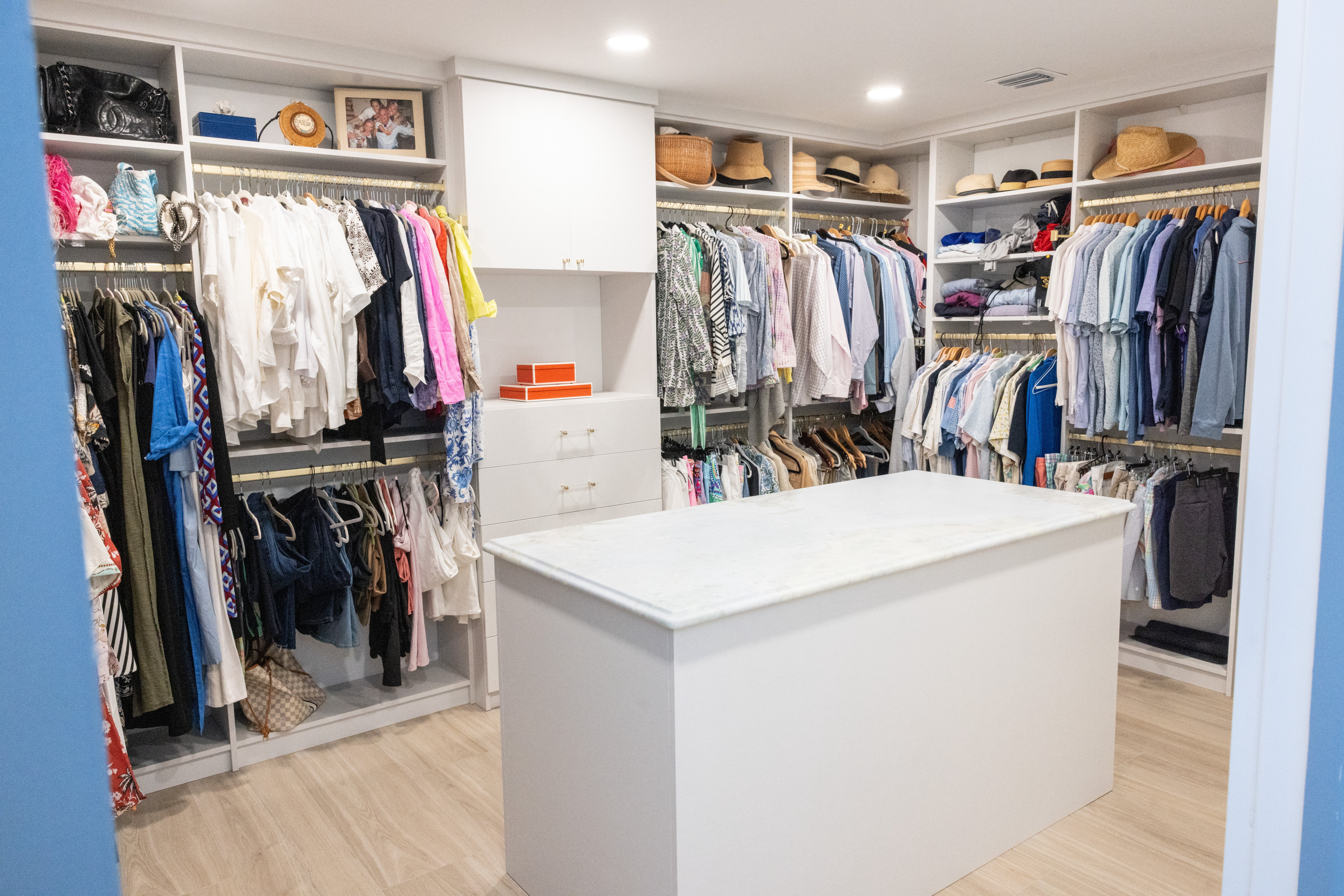 Walk-in closet full view with dual hanging rods, hat shelving, marble center island
