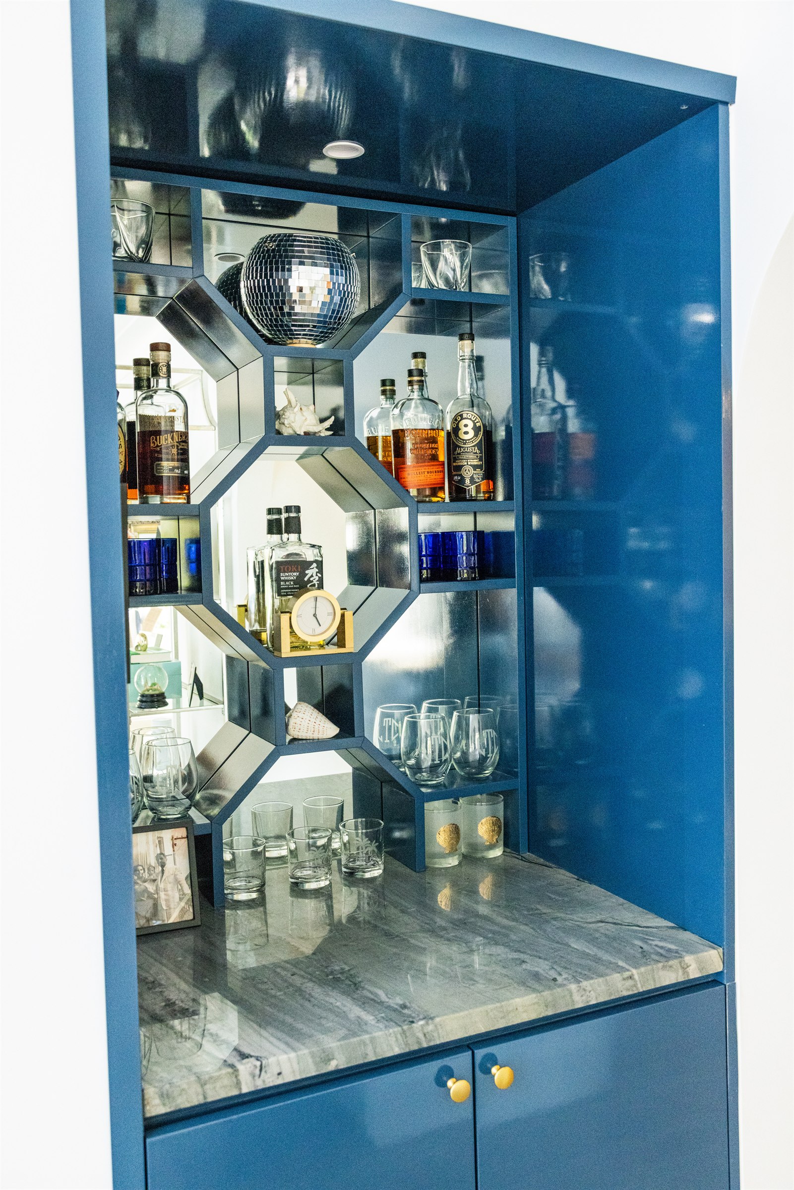 Navy blue mirrored bar cabinet with honeycomb geometric display and a disco ball