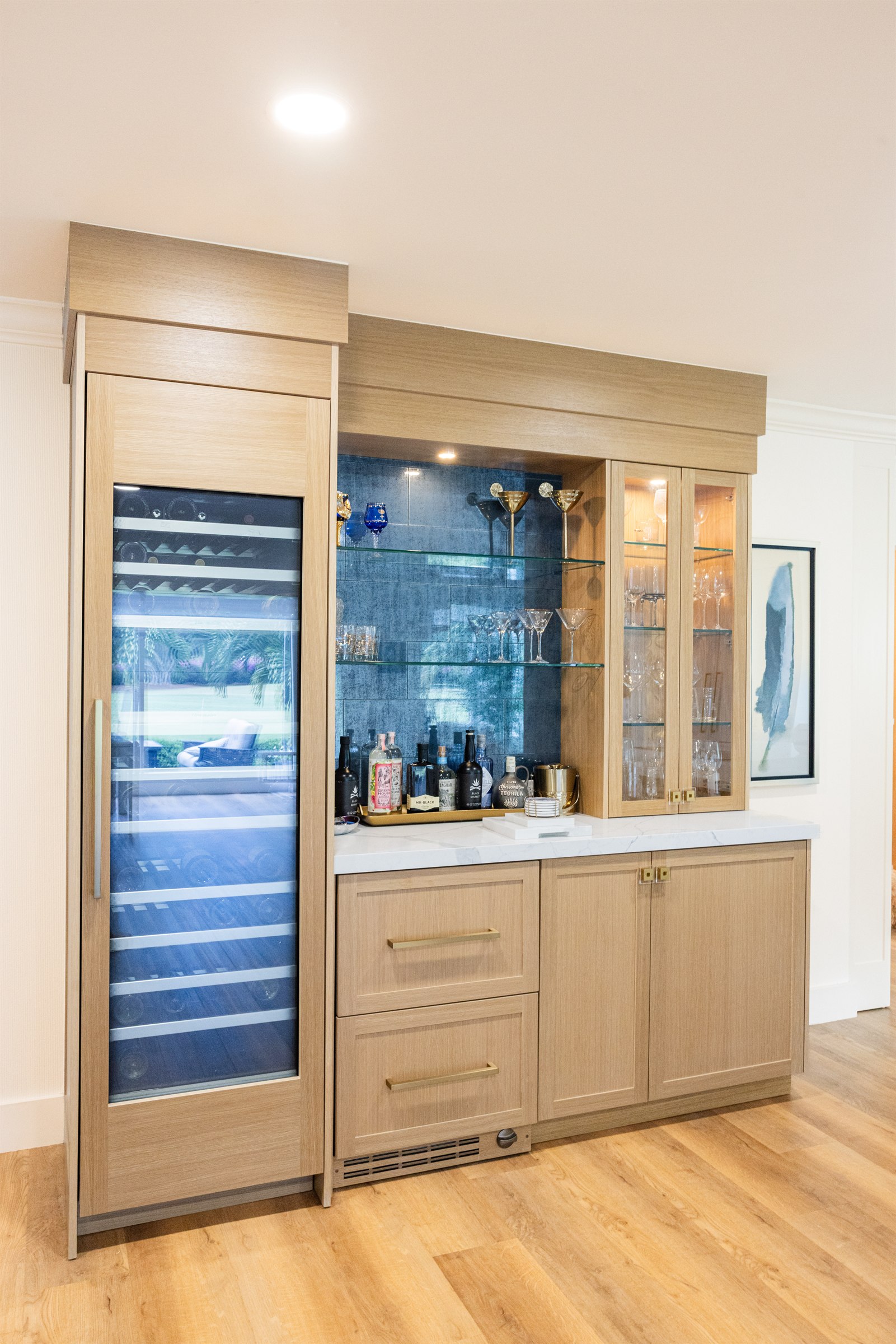 Built-in wood bar with blue tile backsplash, glass shelving, and wine fridge