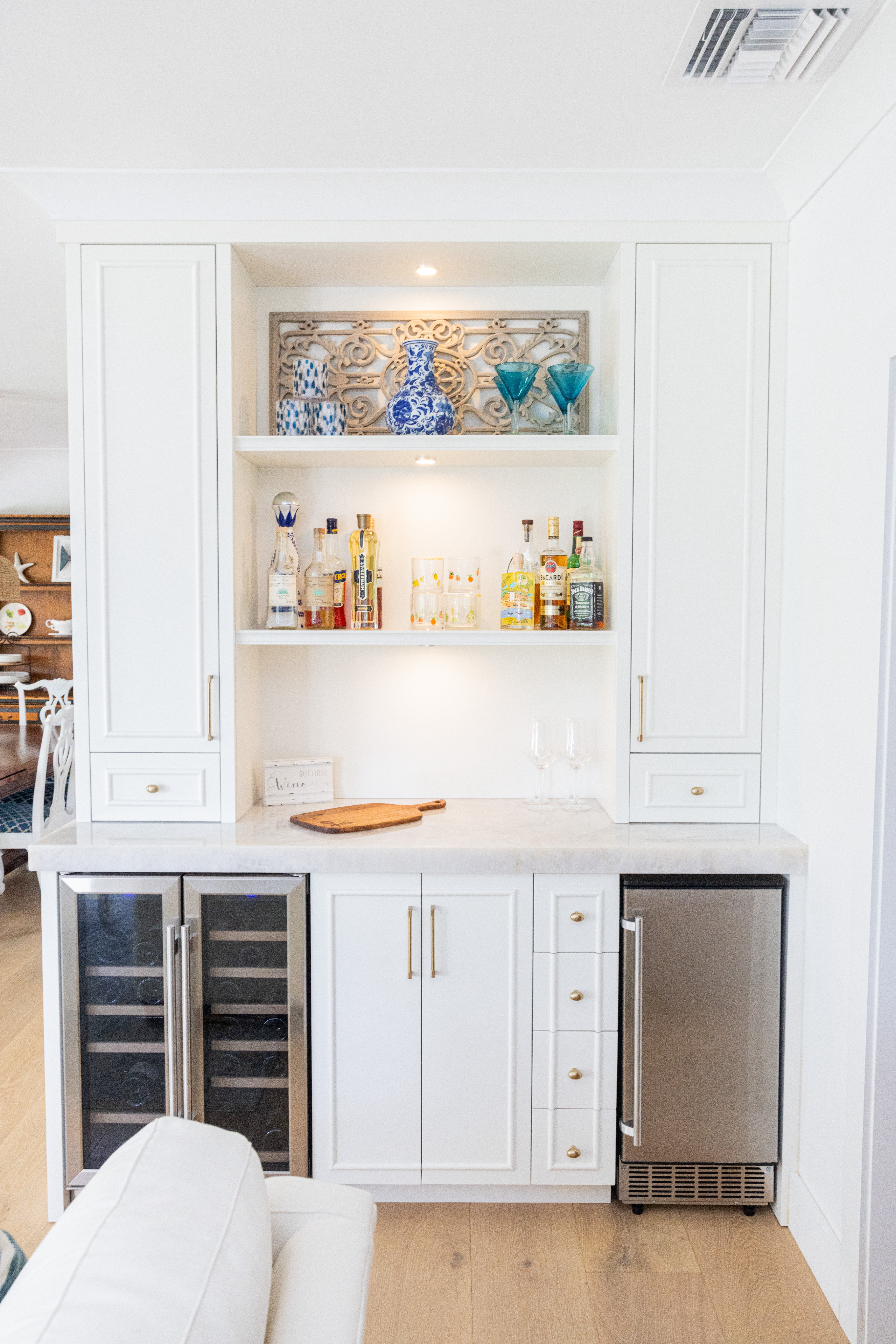 White built-in bar with open shelving, blue and gold glassware