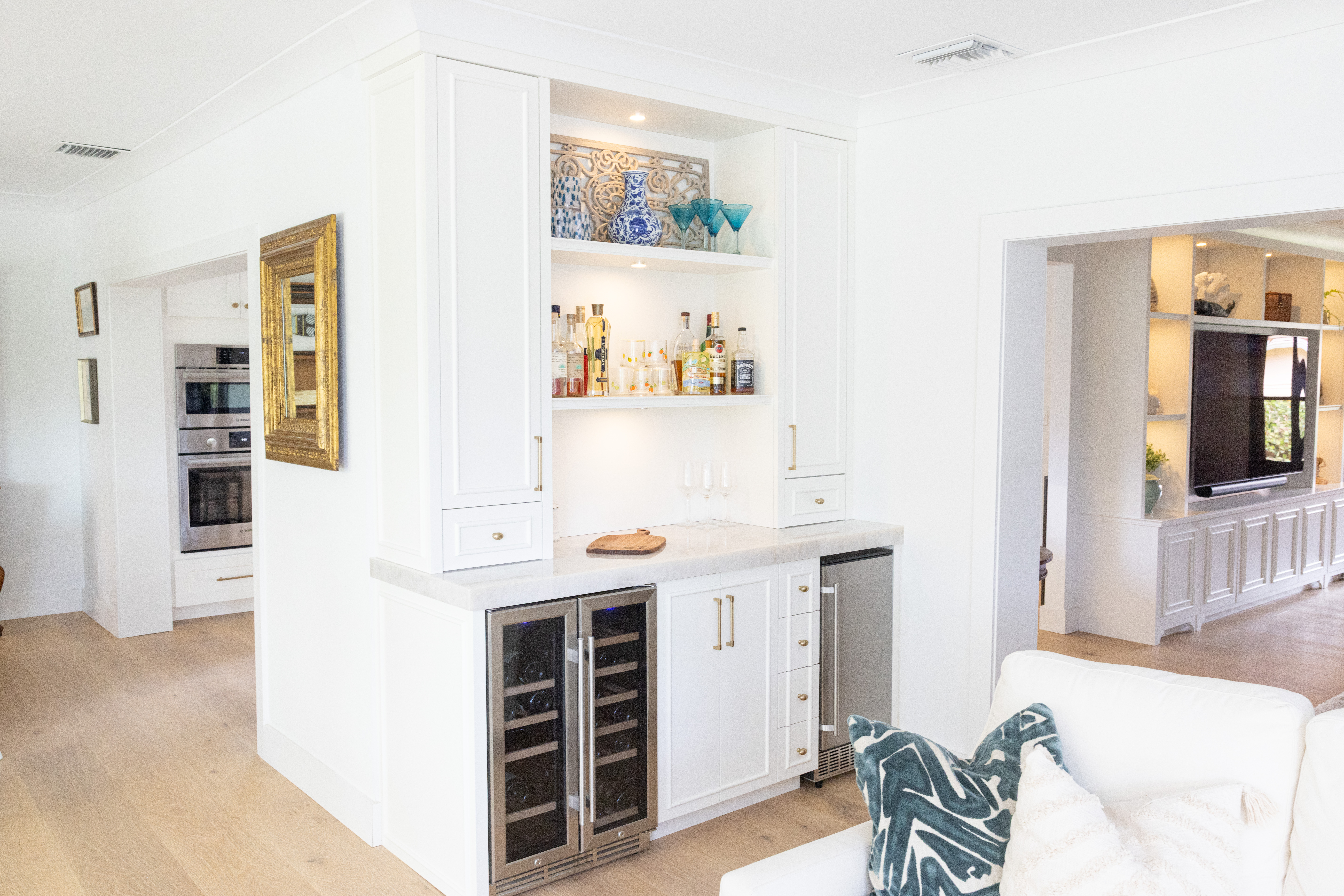 White built-in bar wide view showing wine fridge and living room beyond