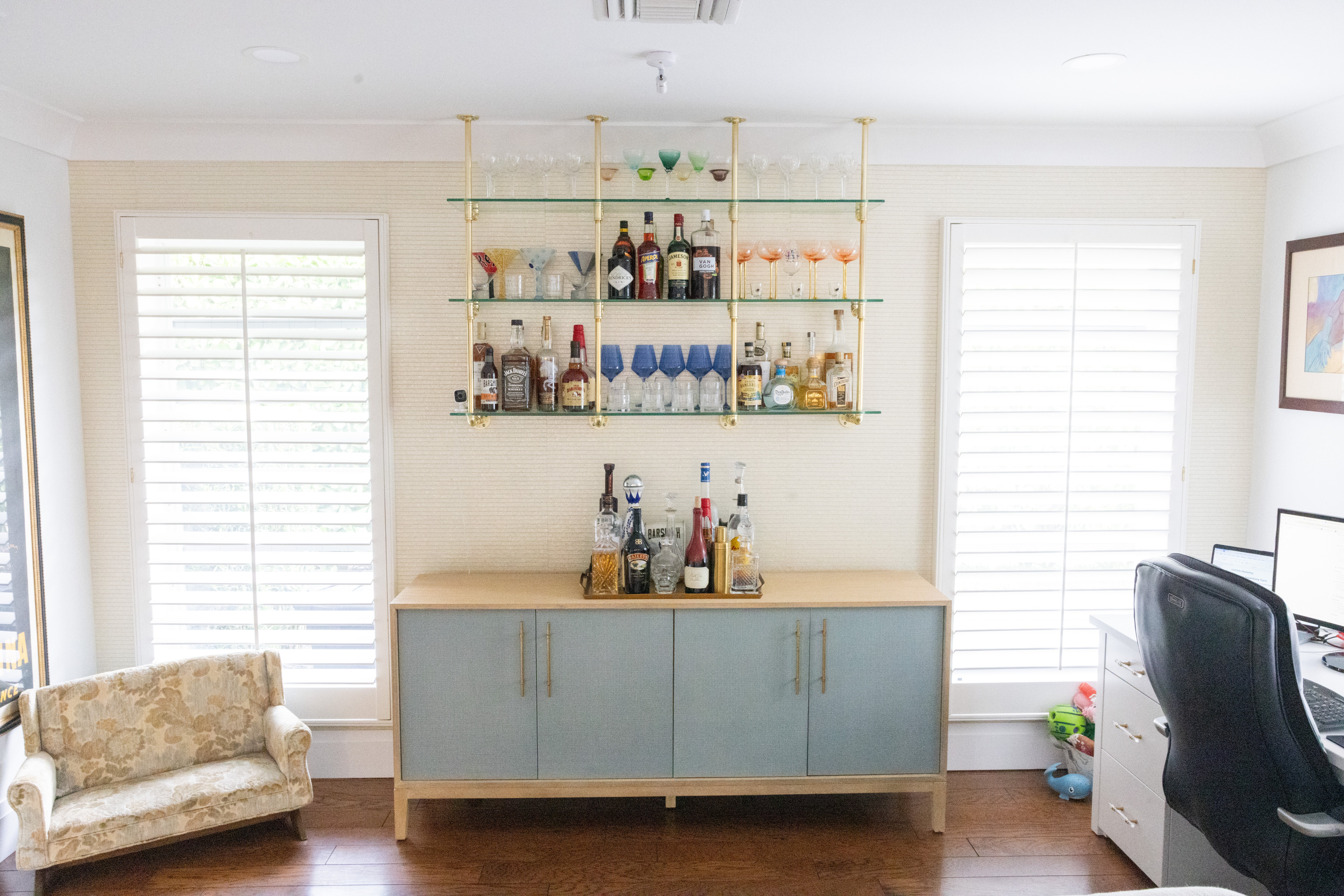 Glass and brass ceiling-hung bar shelving with full bottle collection