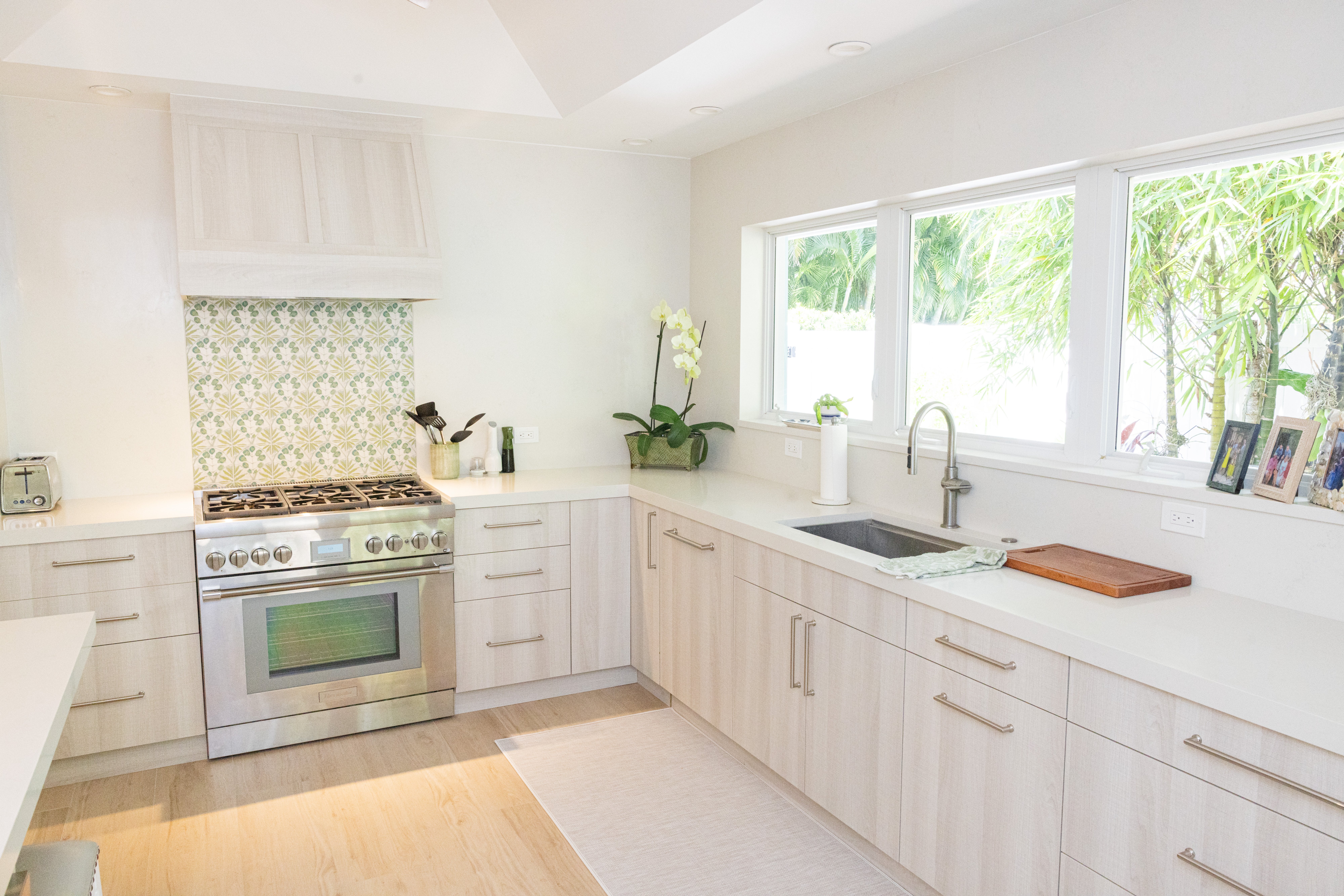 White kitchen with marble island, cane counter stools and open-plan dining