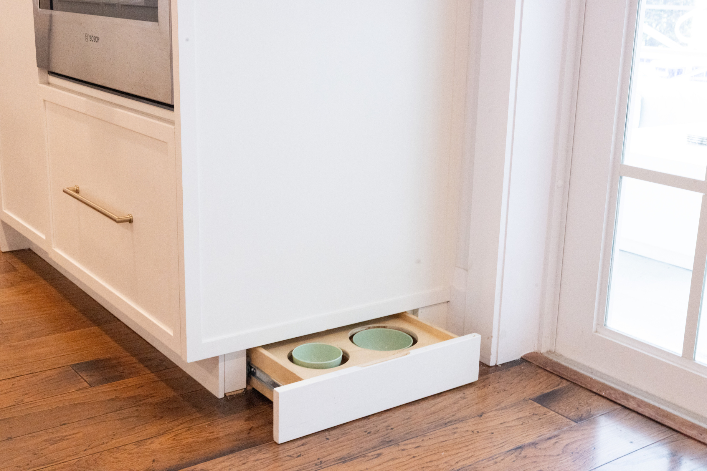Farmhouse sink with brass sconce lighting framing a garden window