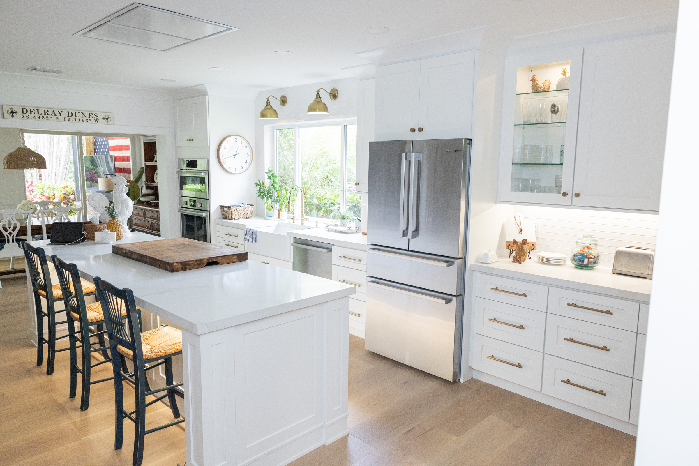 All-white kitchen with marble island and upholstered counter stools