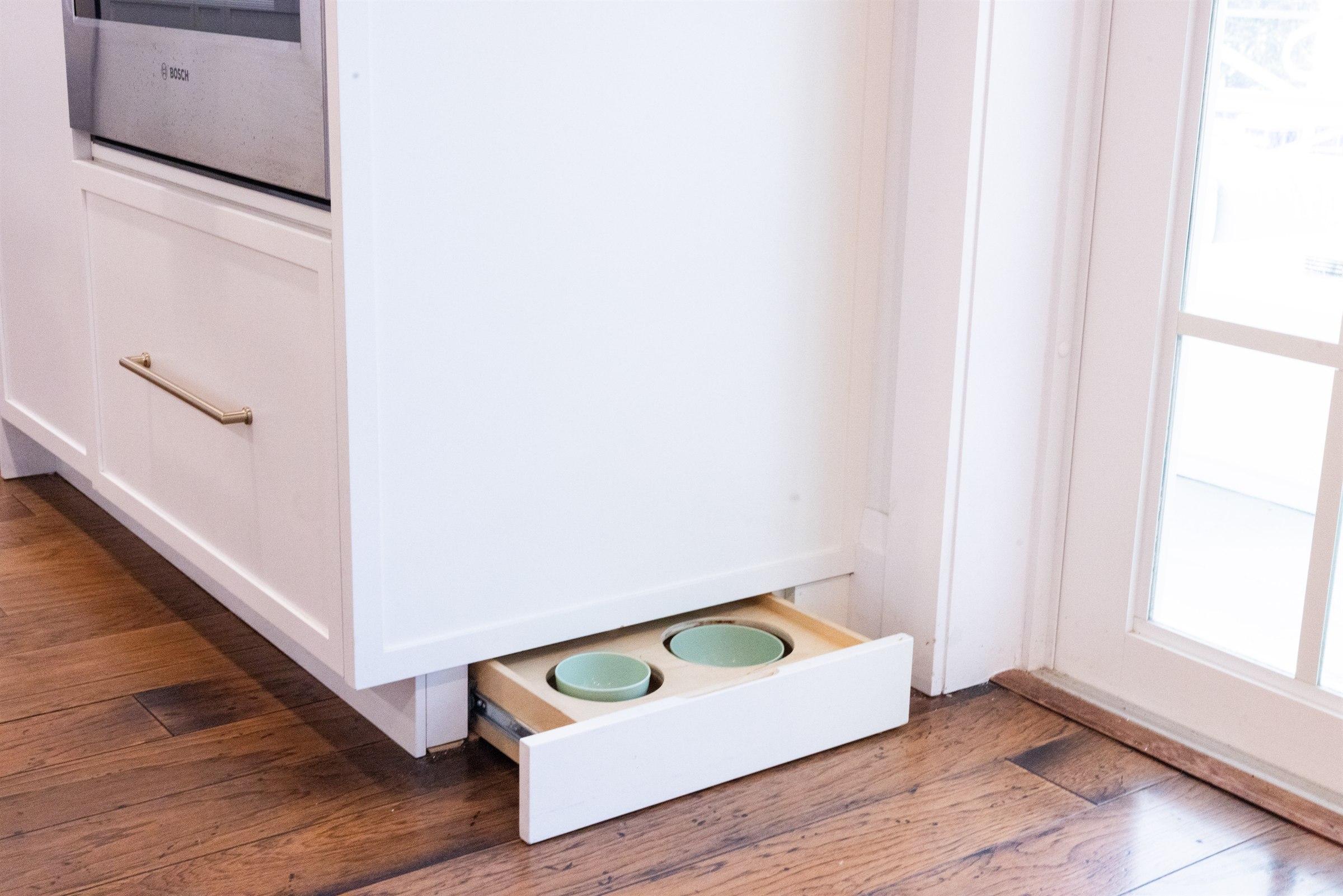 Toe-kick pull-out drawer with pet bowls tucked beside the island