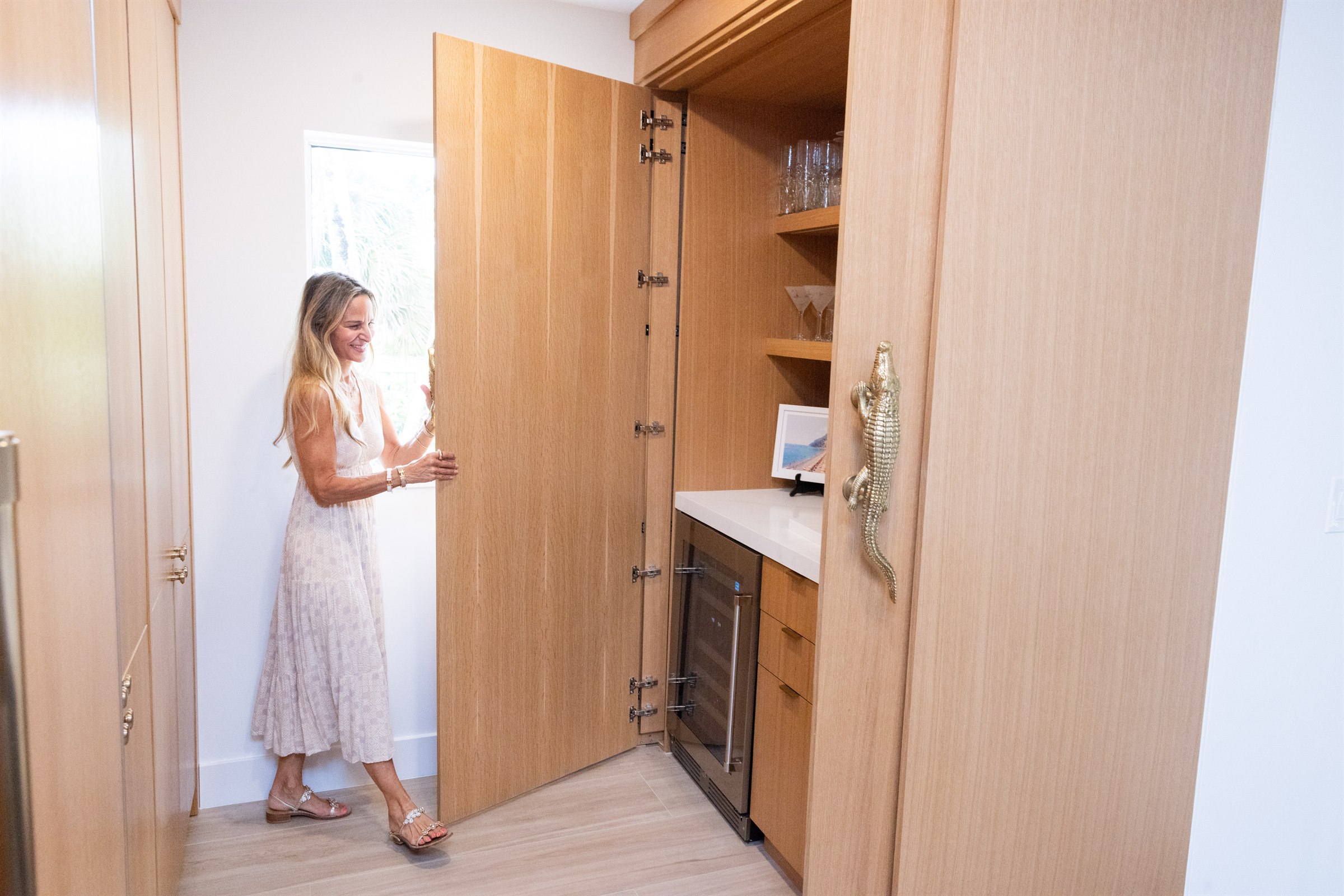 Tall pantry door opening with a brass alligator handle, wine fridge inside