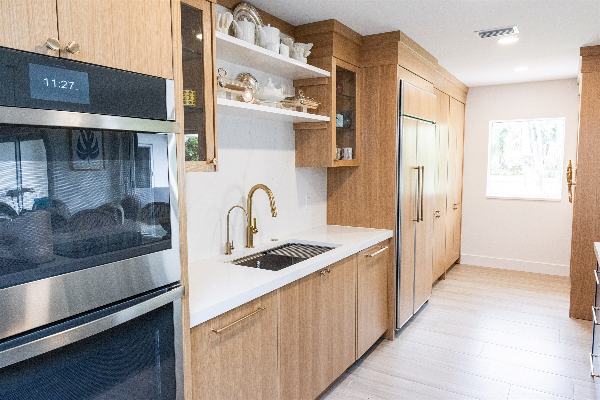 Wood cabinetry wet bar with open shelving, silver serveware, and built-in fridge