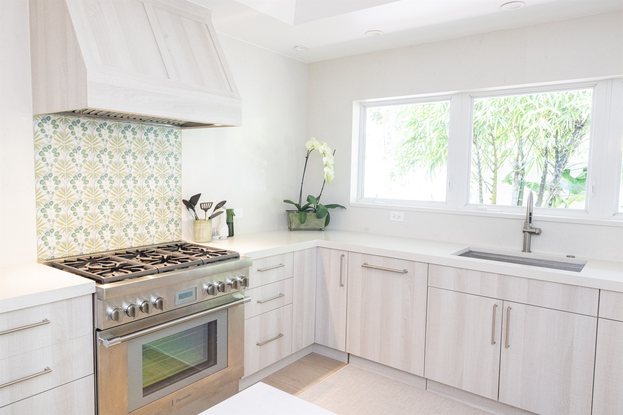 Closer view of the range, green floral tile backsplash, and prep sink
