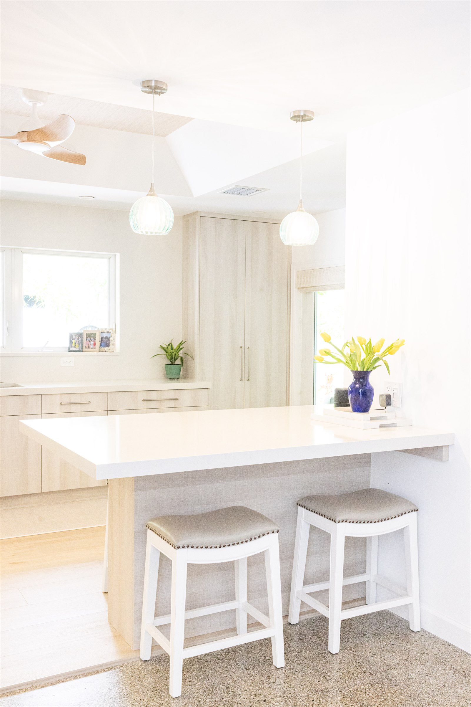 Pass-through counter with pendant lighting and white counter stools
