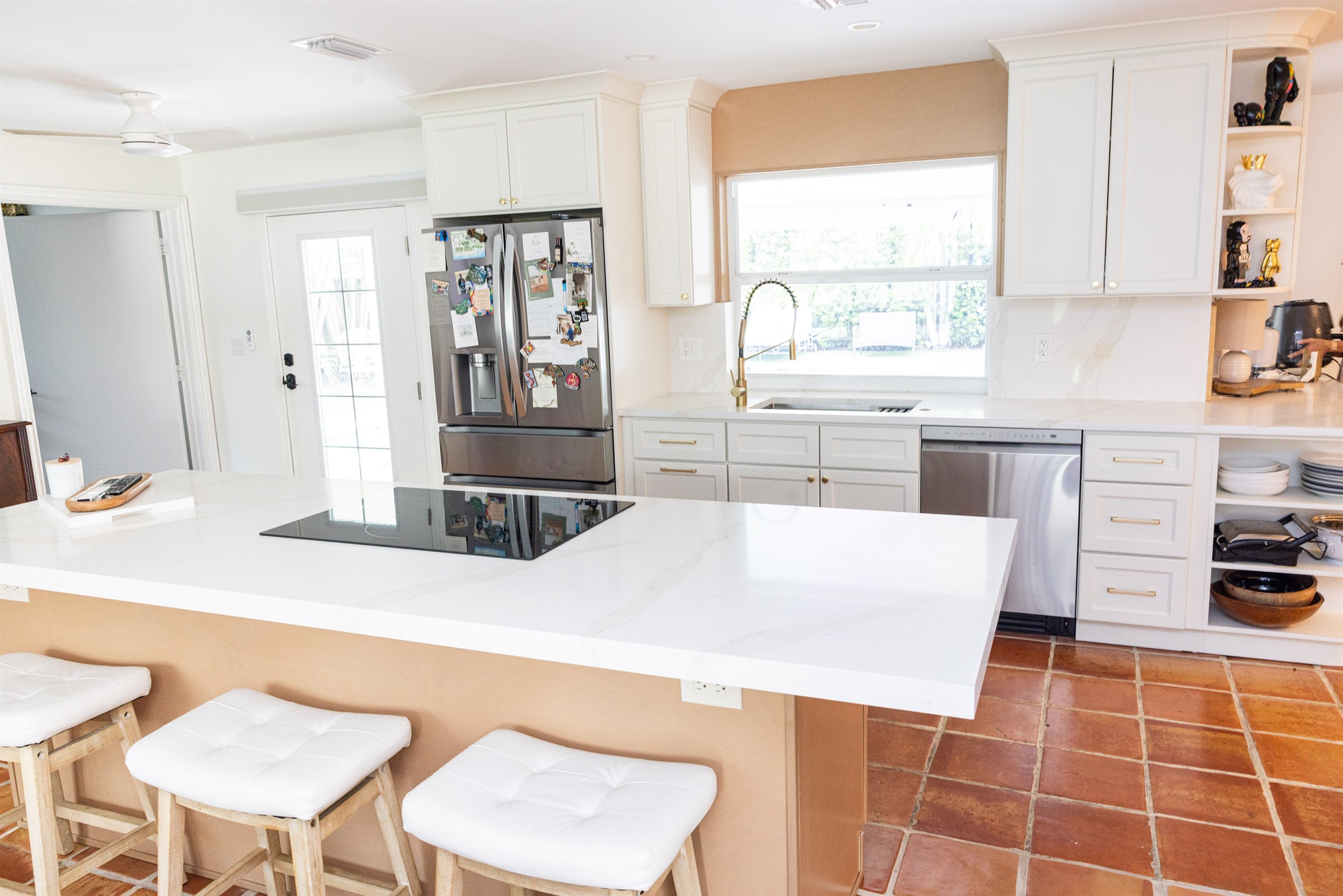 Traditional white kitchen with terracotta tile floor and stainless refrigerator