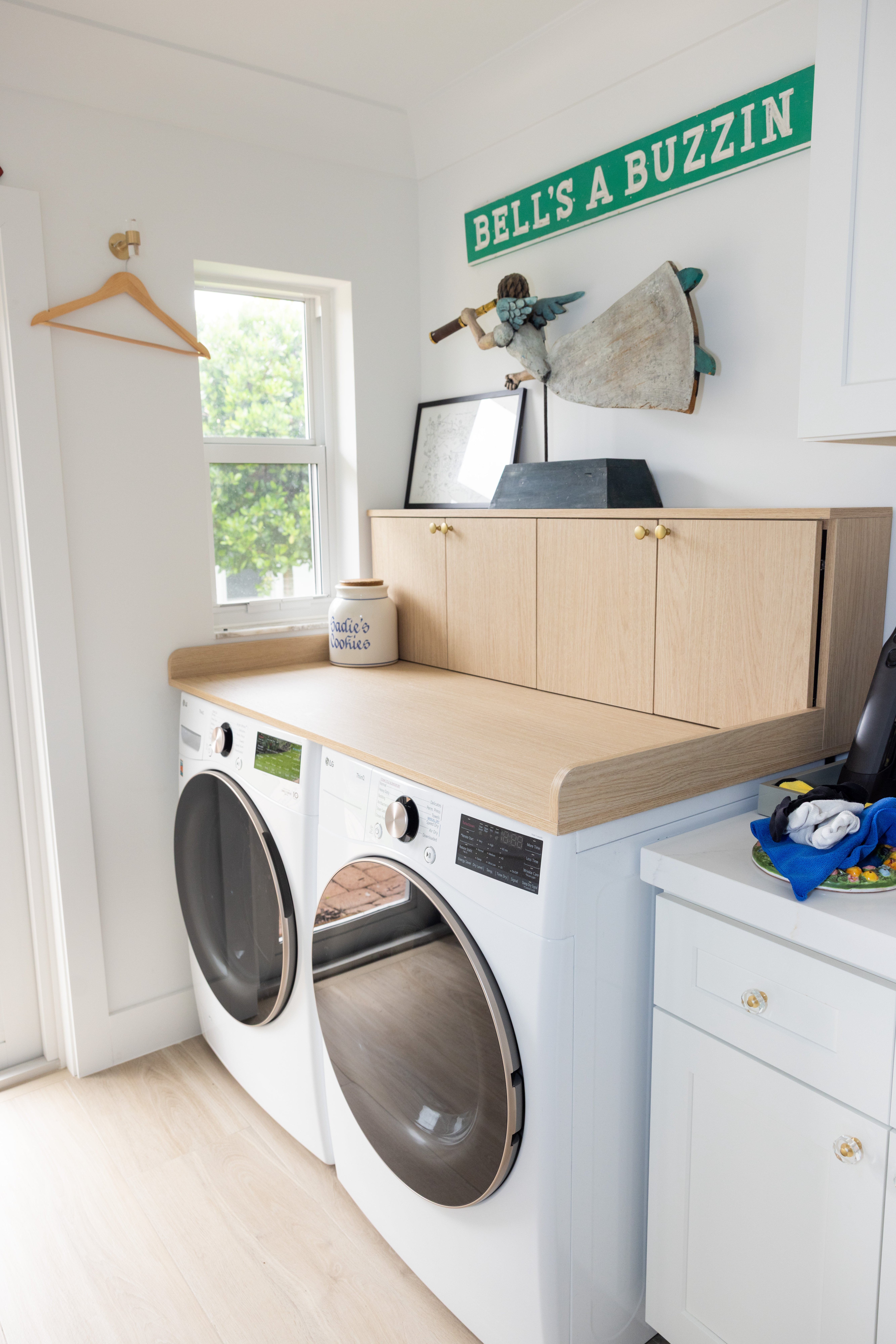 Bright laundry room with LG machines, oak countertop and playful signage