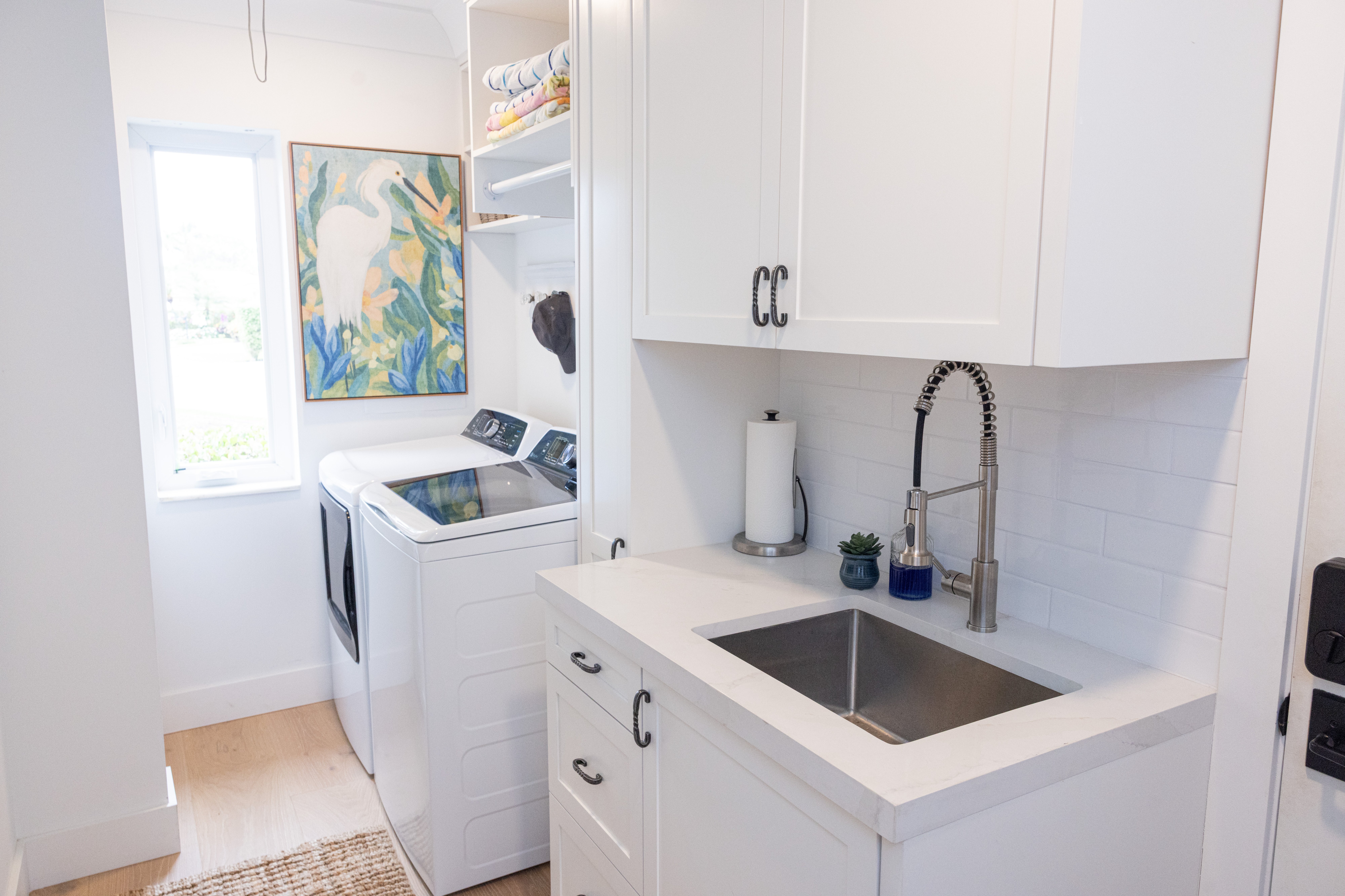 Laundry room with whimsical monkey wallpaper, taupe cabinetry and Electrolux machines