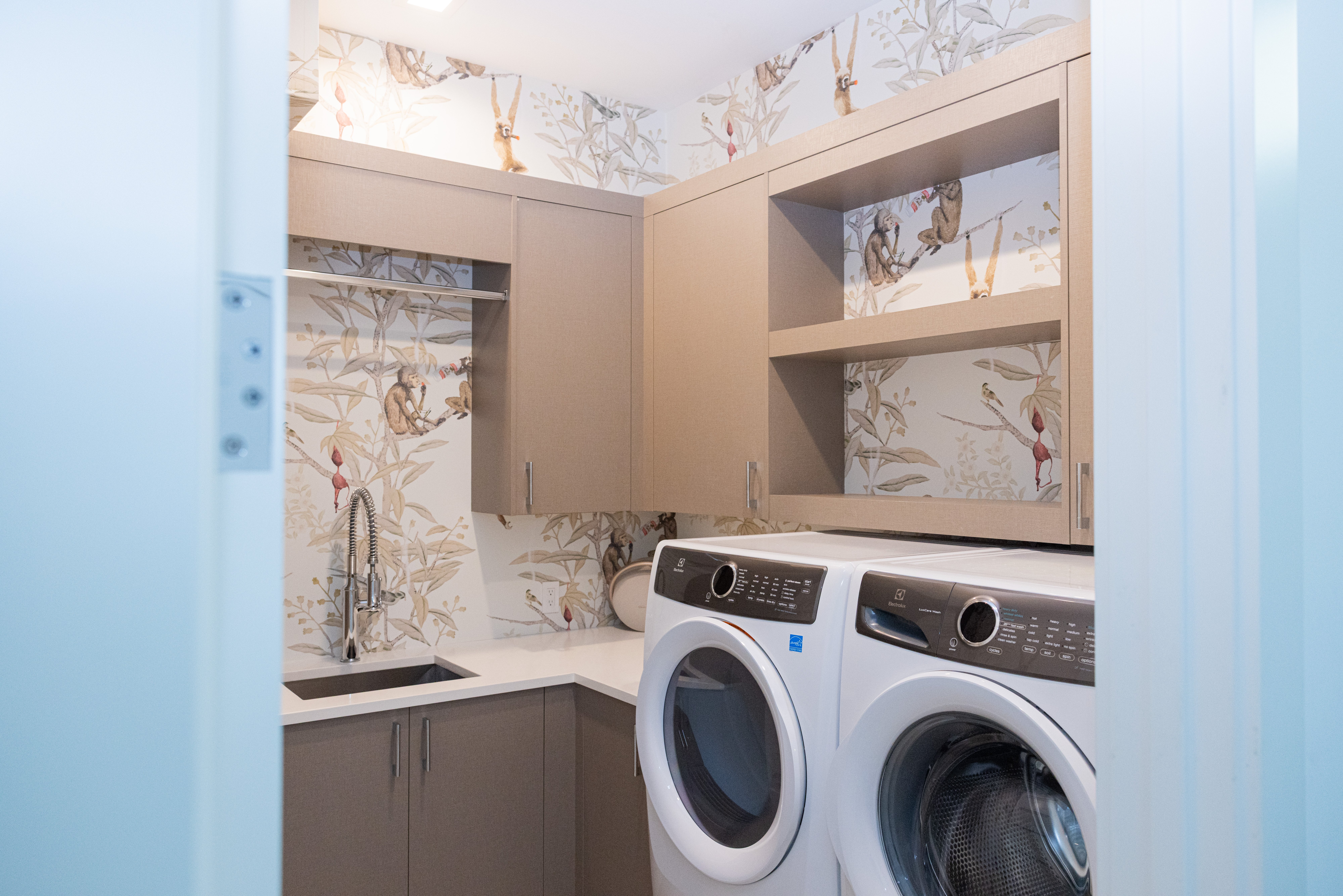 Laundry room with white cabinetry, egret artwork and stainless utility sink