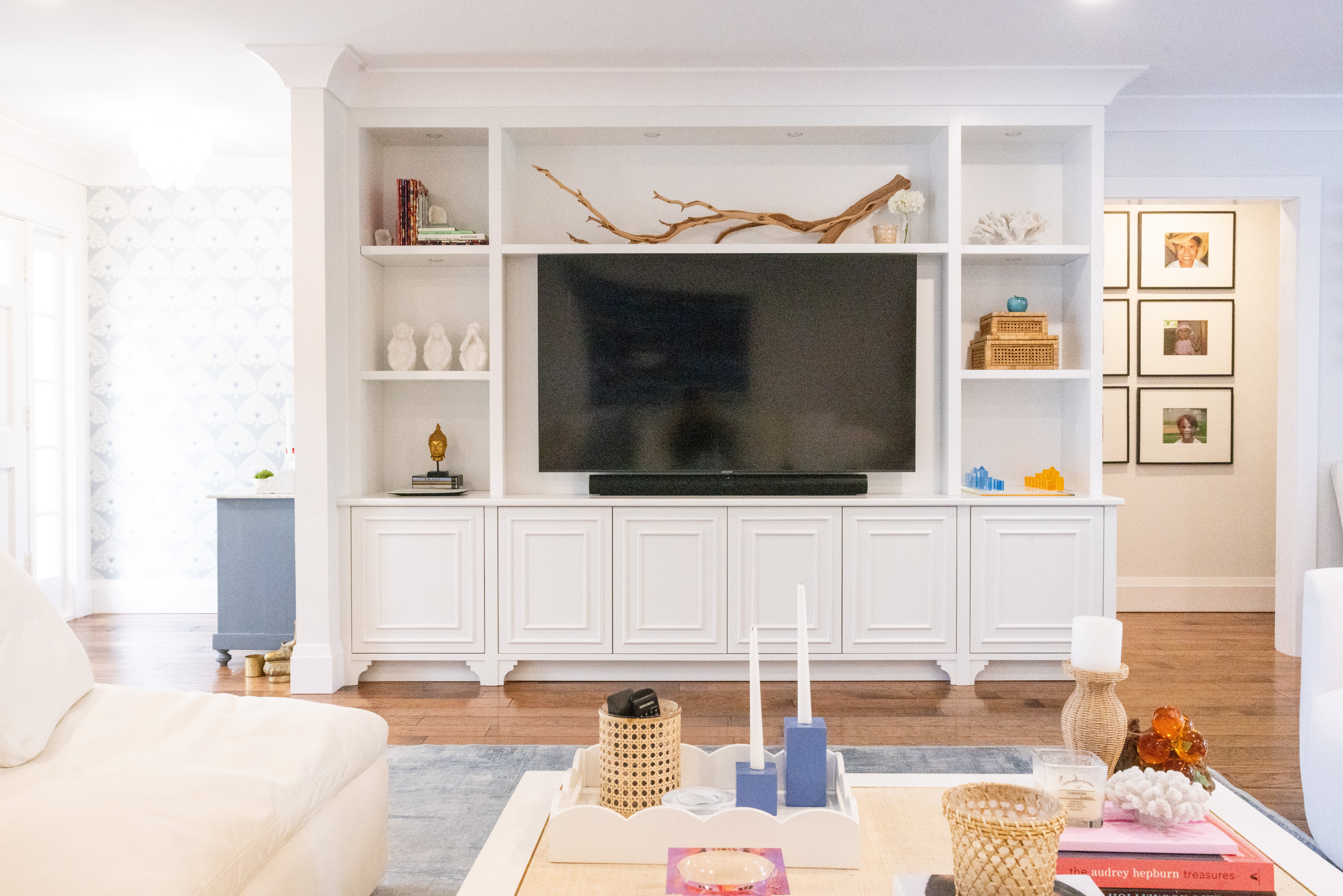 Wide living room view showing navy accent chairs, grasscloth-style rug and garden views