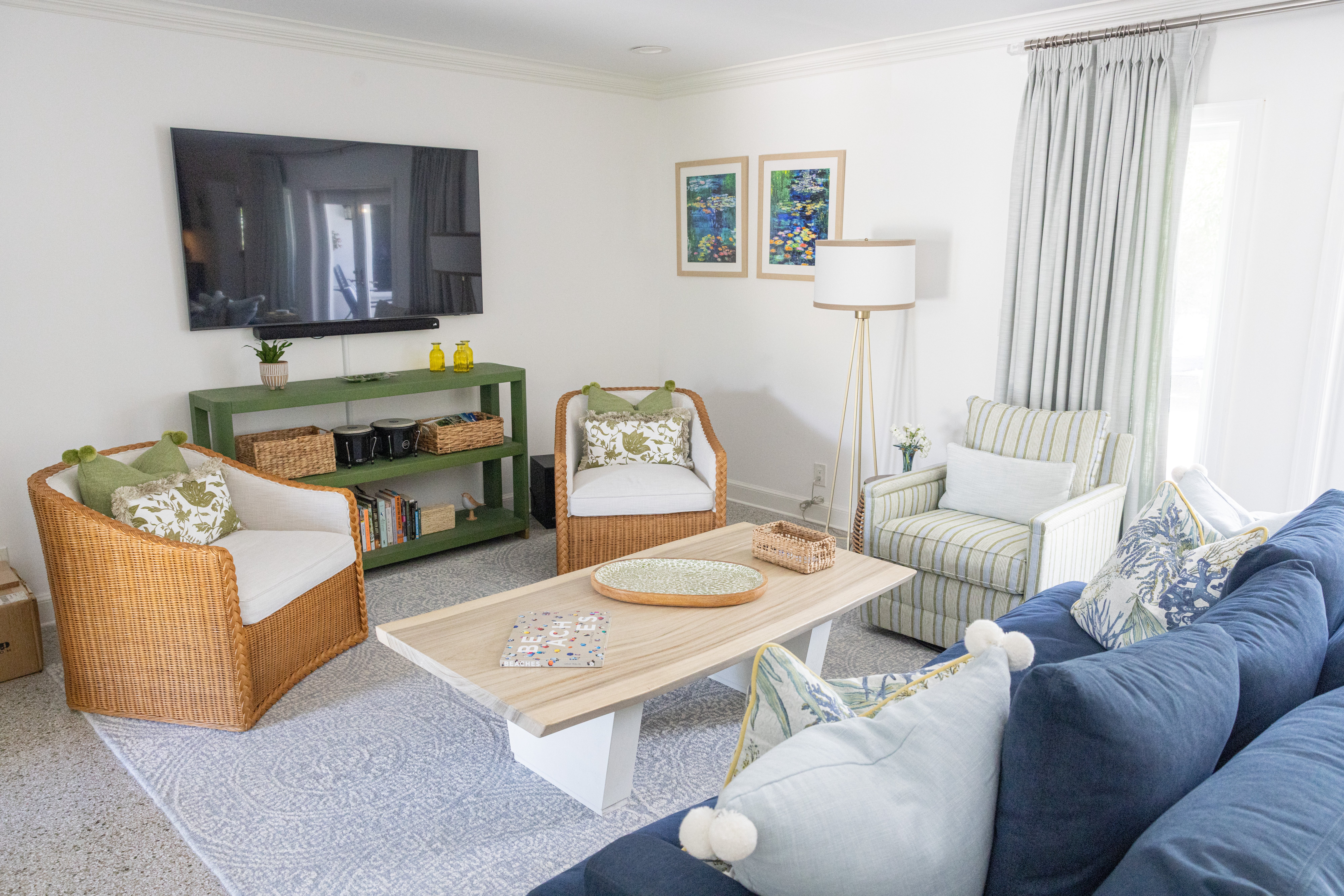 Casual living room with wicker barrel chairs, green console and navy velvet sofa