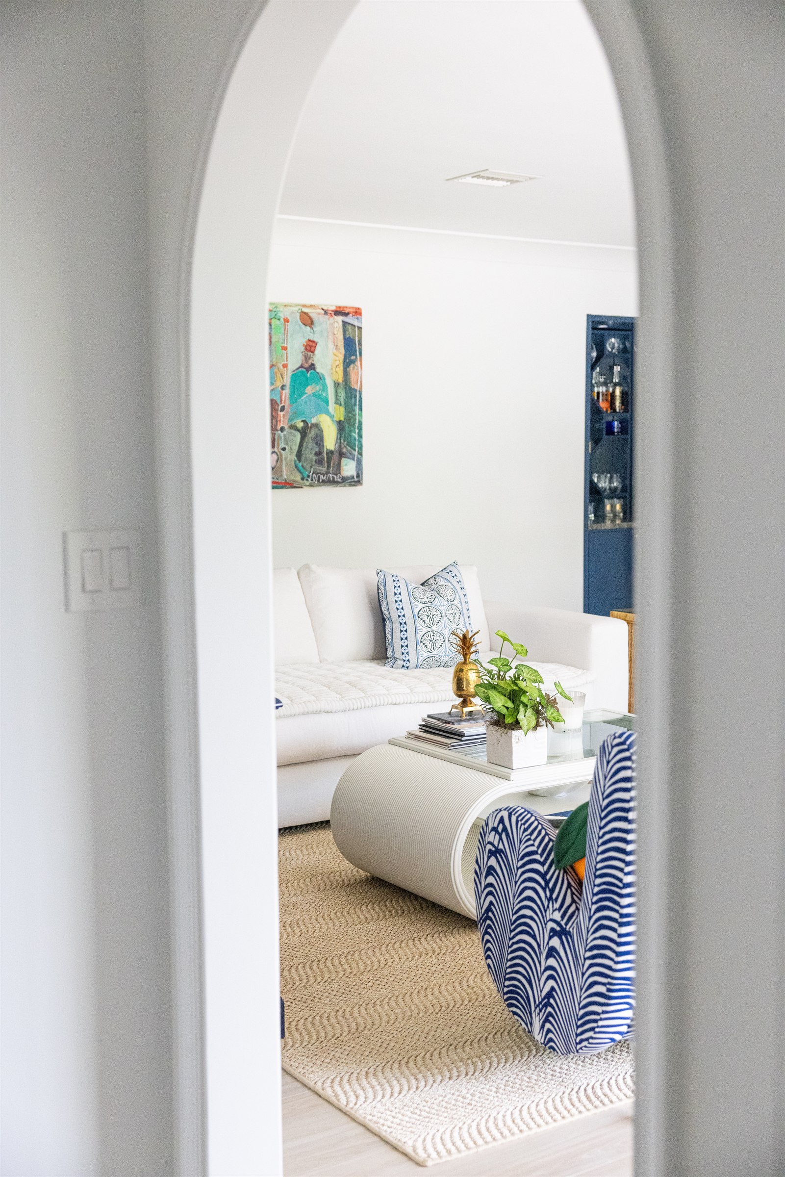 View through an arched doorway into an adjoining sitting room with block-print pillows