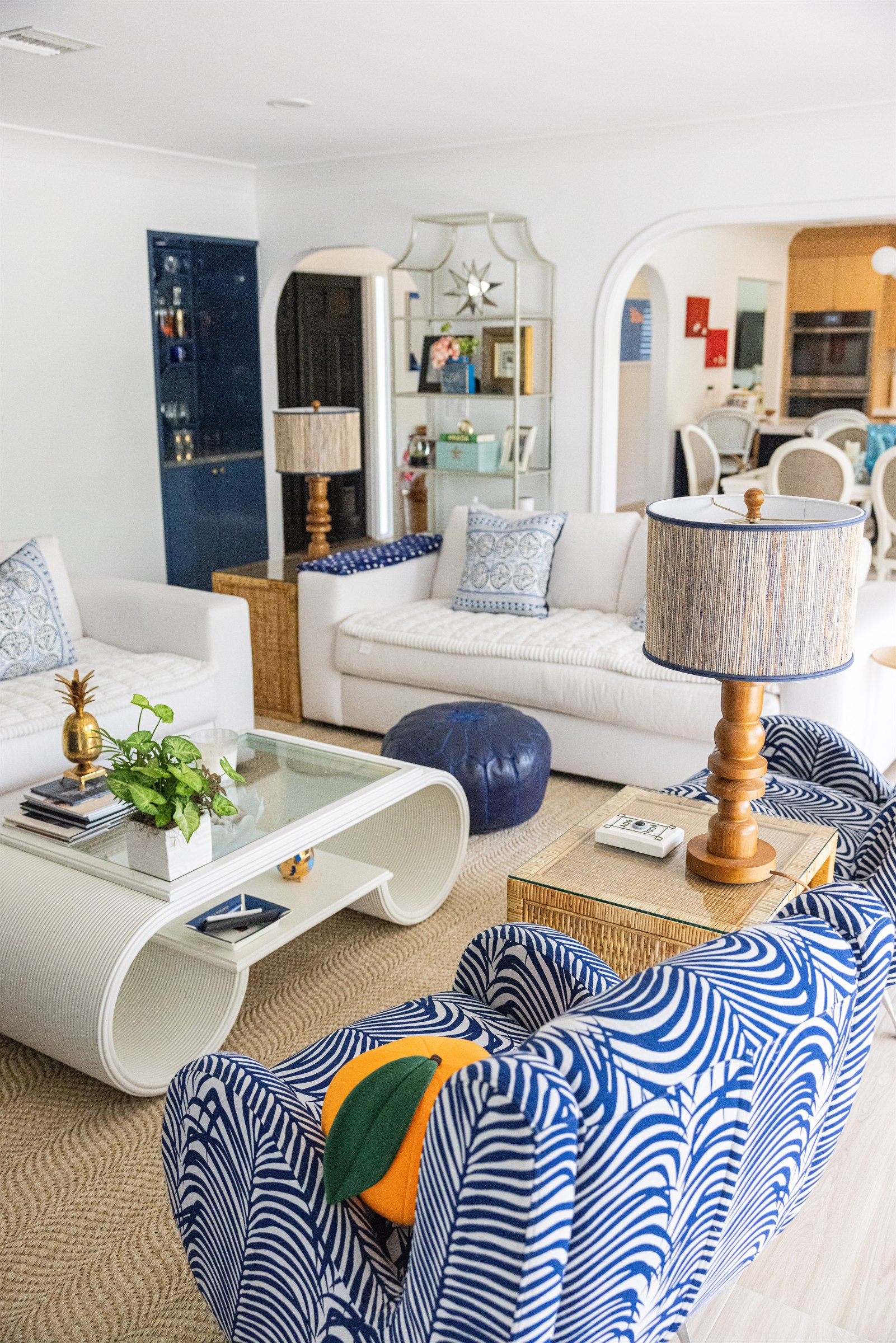 Sitting room with navy bar cabinet, brass pineapple lamp, and blue palm-print swivel chairs