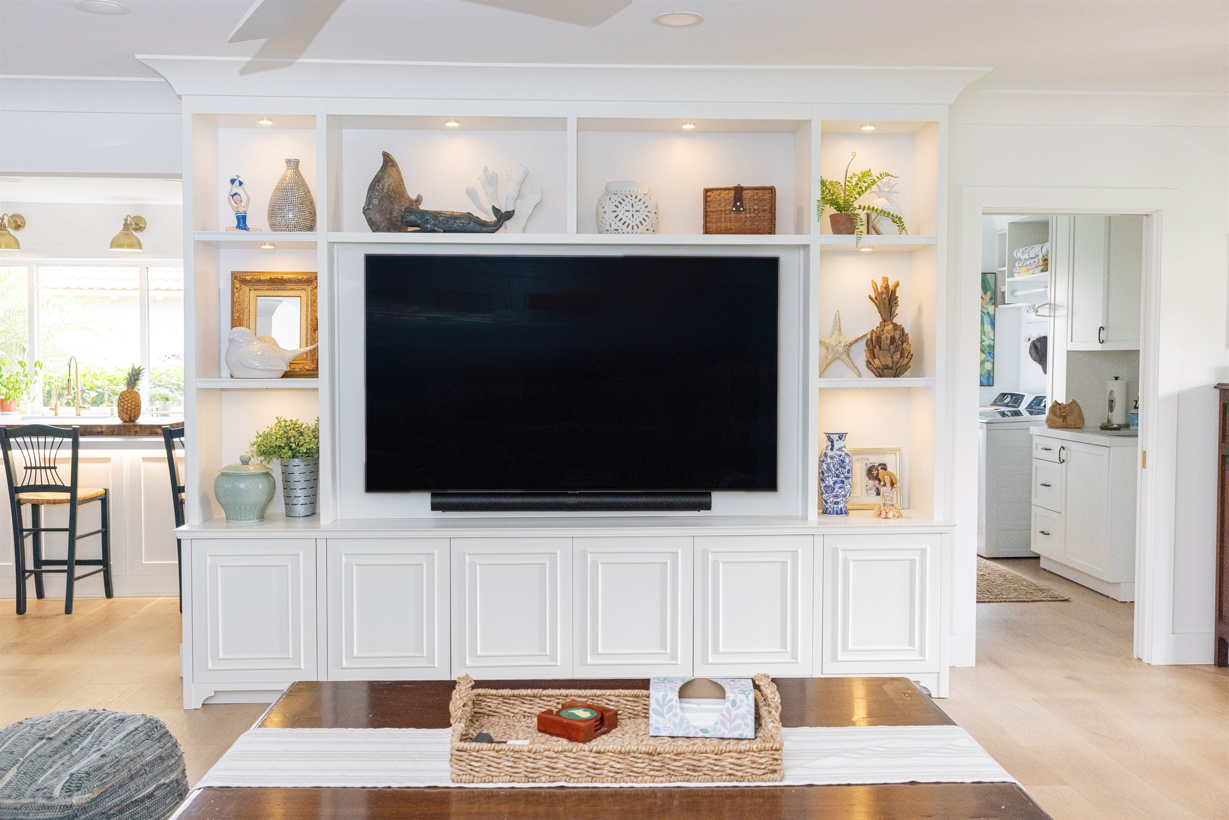 Built-in entertainment wall styled with whale and coral sculptures and a gilt mirror