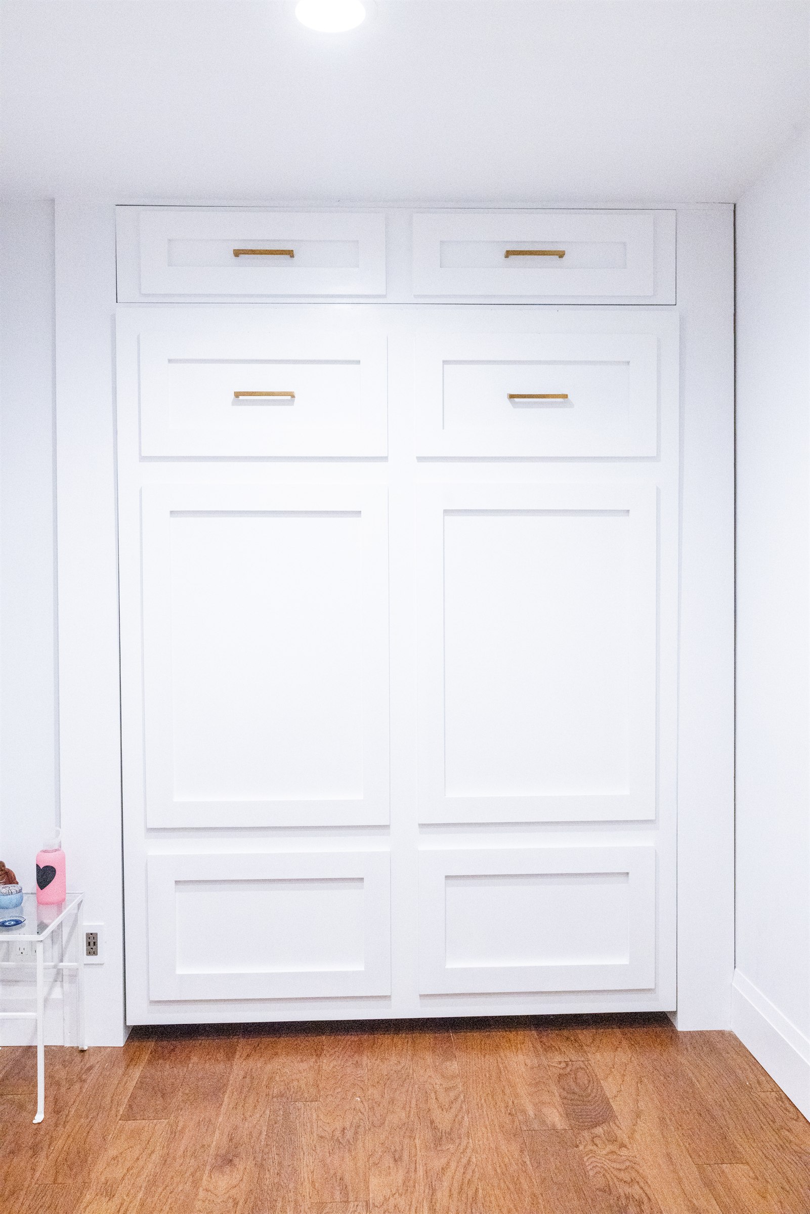 Murphy bed cabinetry closed, presenting as a full wall of white paneled storage