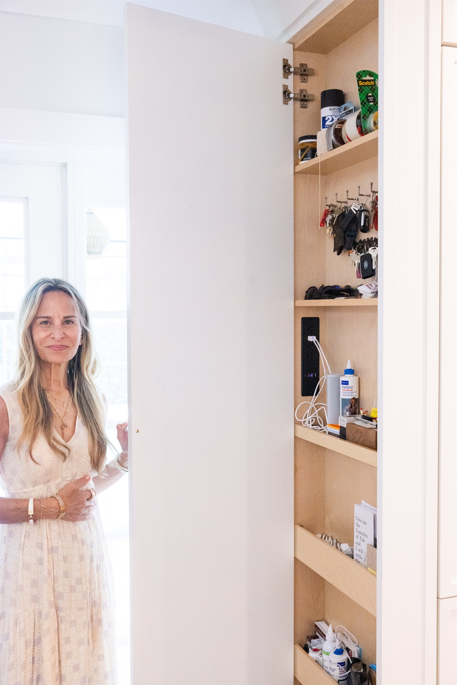 Designer opening a tall built-in closet organized with keys, sunglasses, and everyday essentials