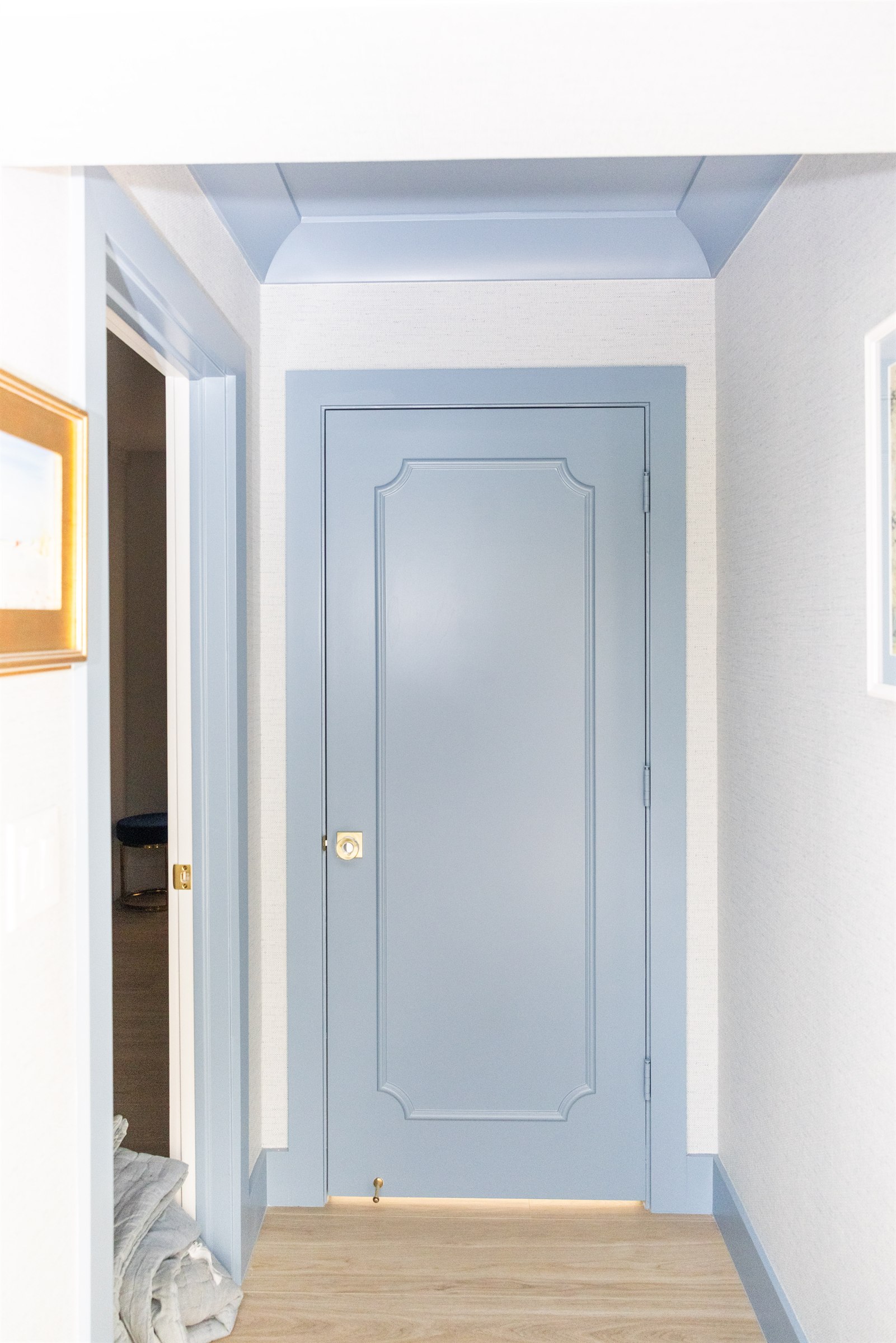 Hallway with a custom powder-blue paneled door and picture-frame trim