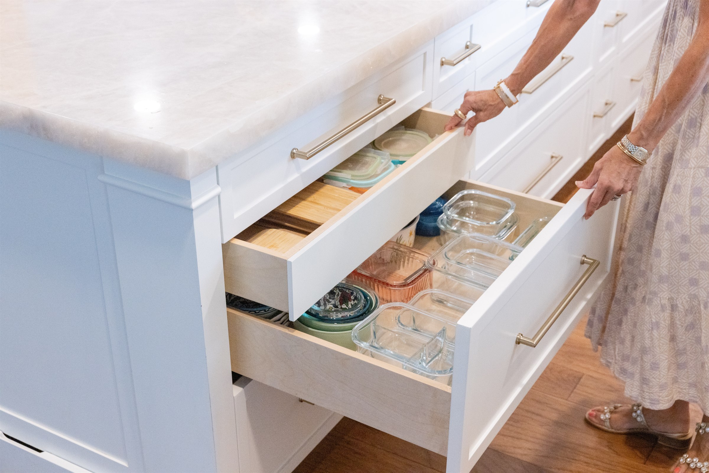 Deep kitchen island drawers organized with glass storage containers and serveware